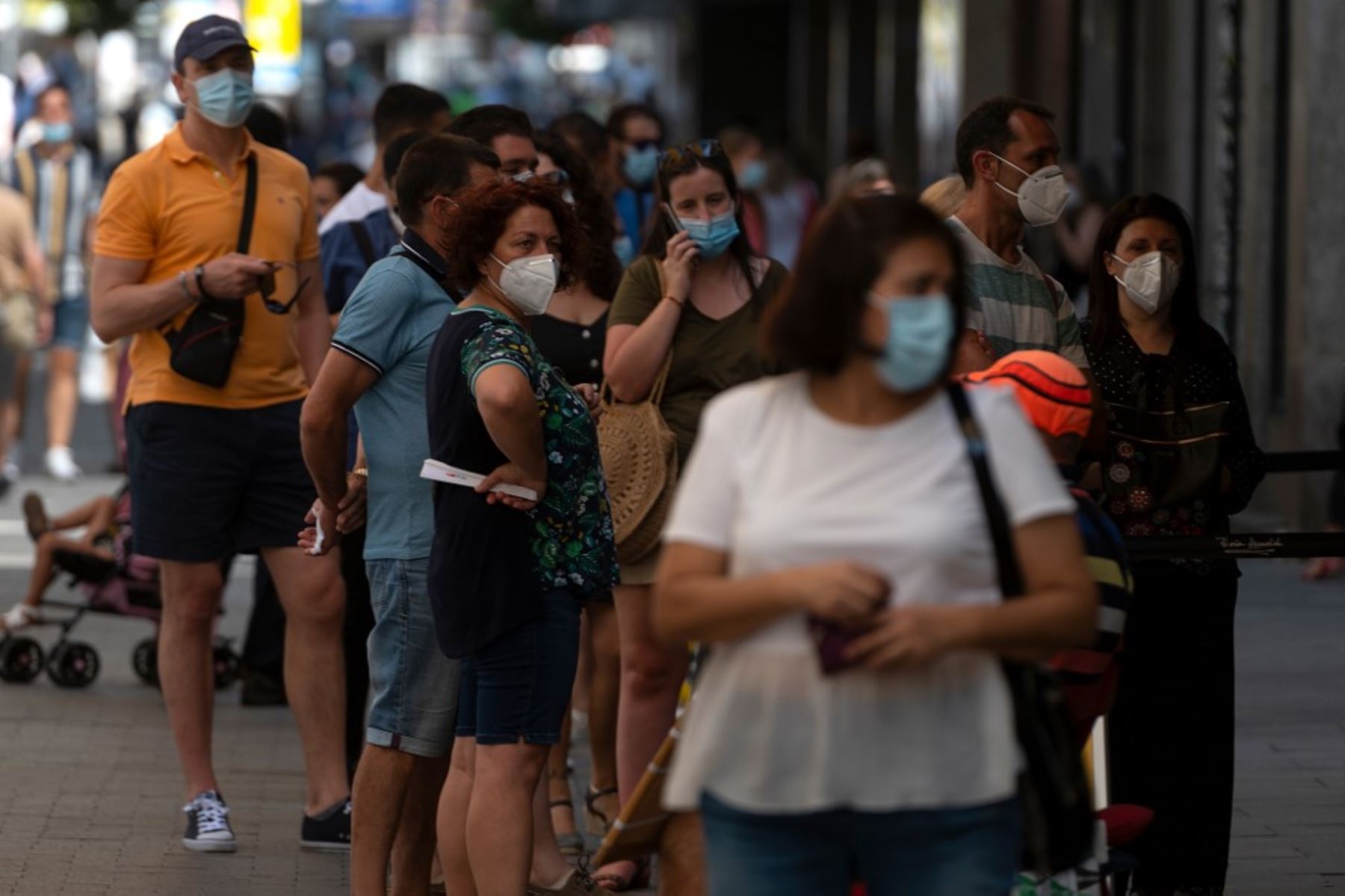 Las personas que usan máscaras hacen cola para comprar boletos de lotería en el centro de Madrid. Foto: AFP