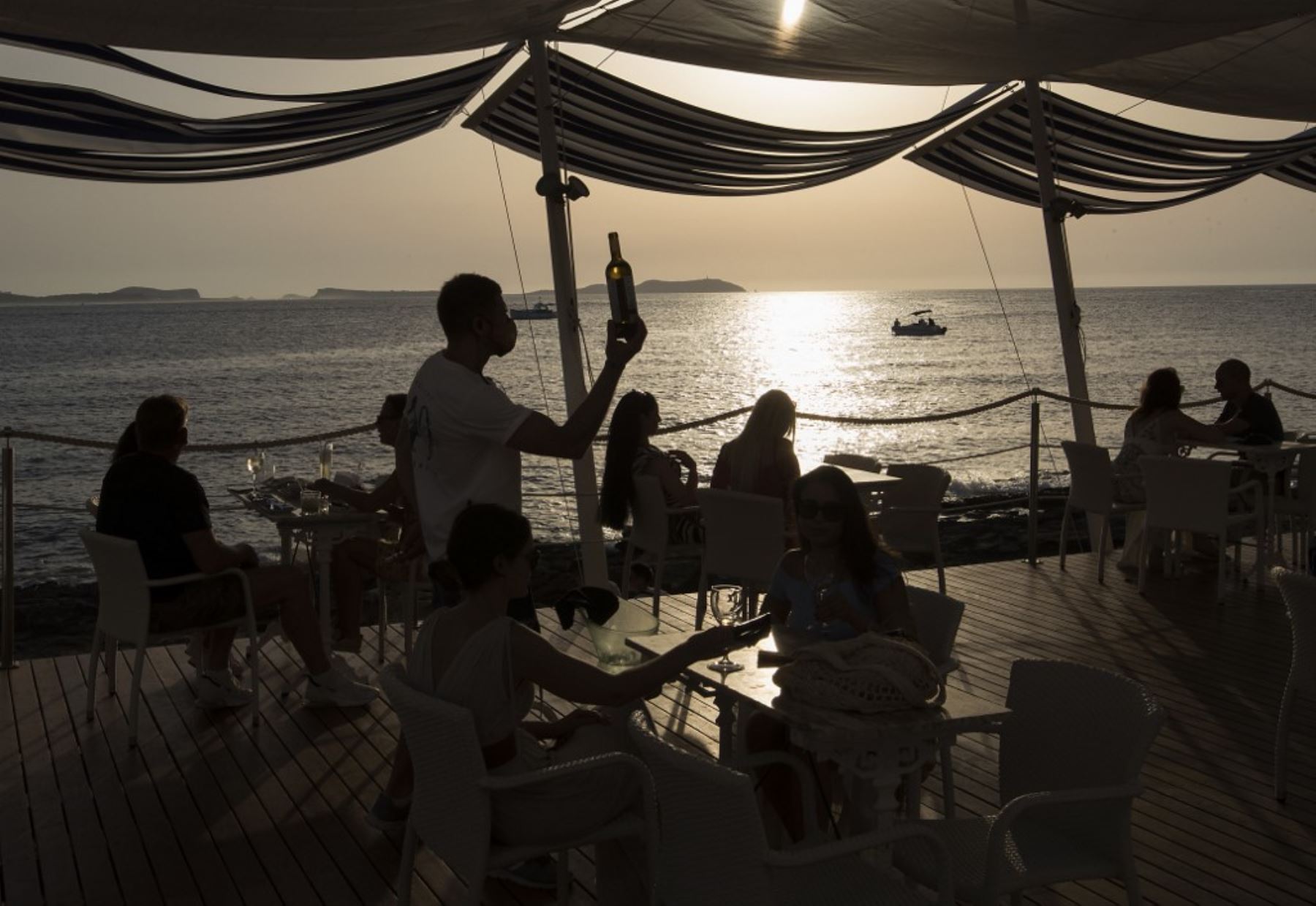 Los turistas se sientan en el bar con terraza "Cafe del Mar" en Sant Antoni de Portmany. Foto: AFP