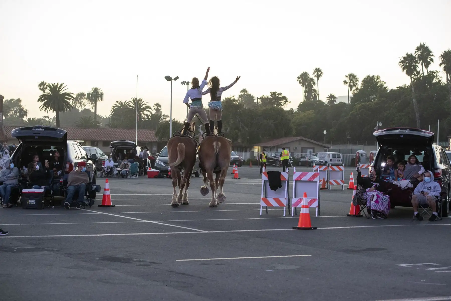 Dos artistas del Zoppe Italian Family Circus montan sus caballos entre los automóviles durante el evento en vivo 