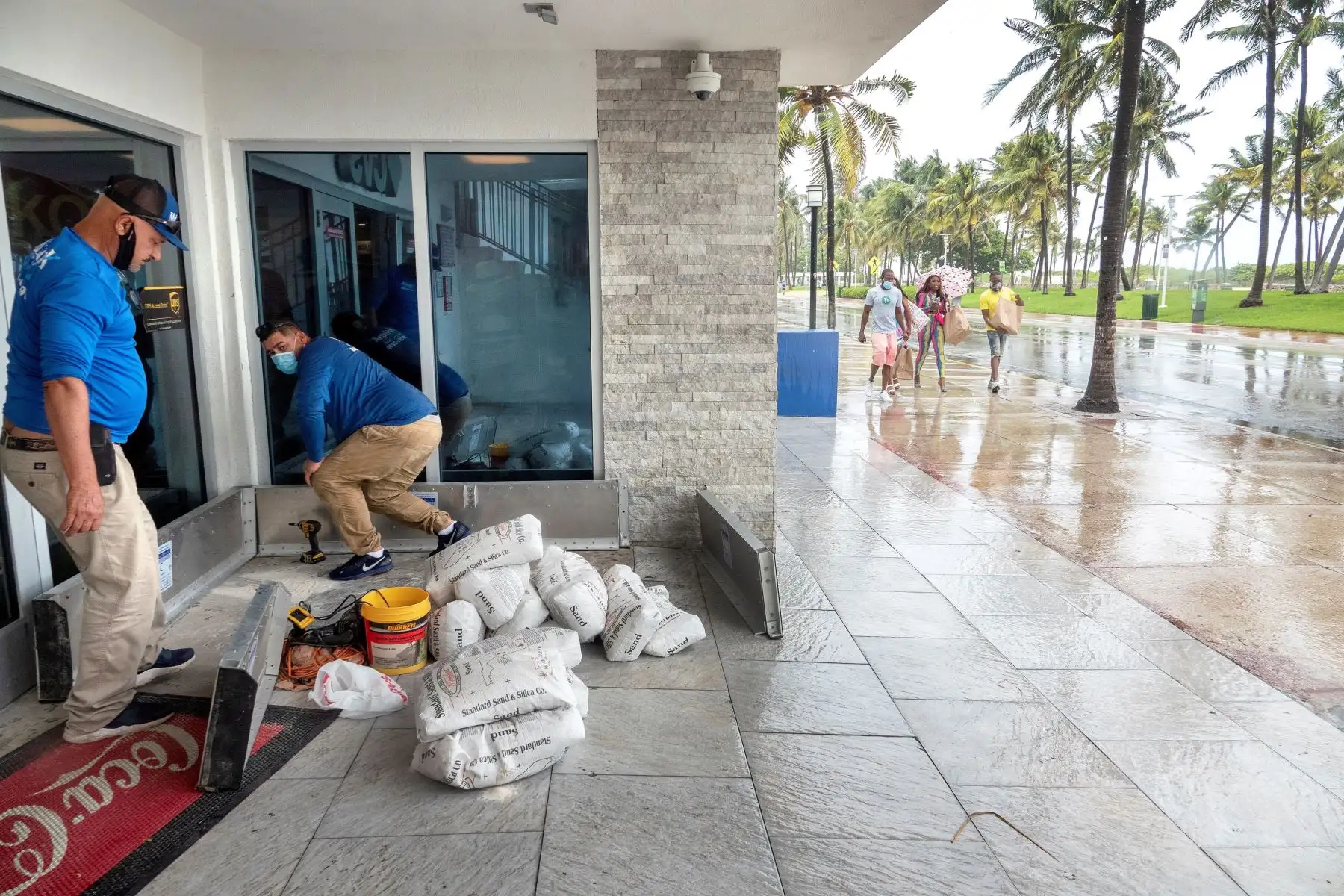 Trabajadores instalan paneles y bolsas de arena como contención en la entrada de una farmacia en Miami Beach, Florida; ante el paso del Huracán Isaías. Foto: EFE