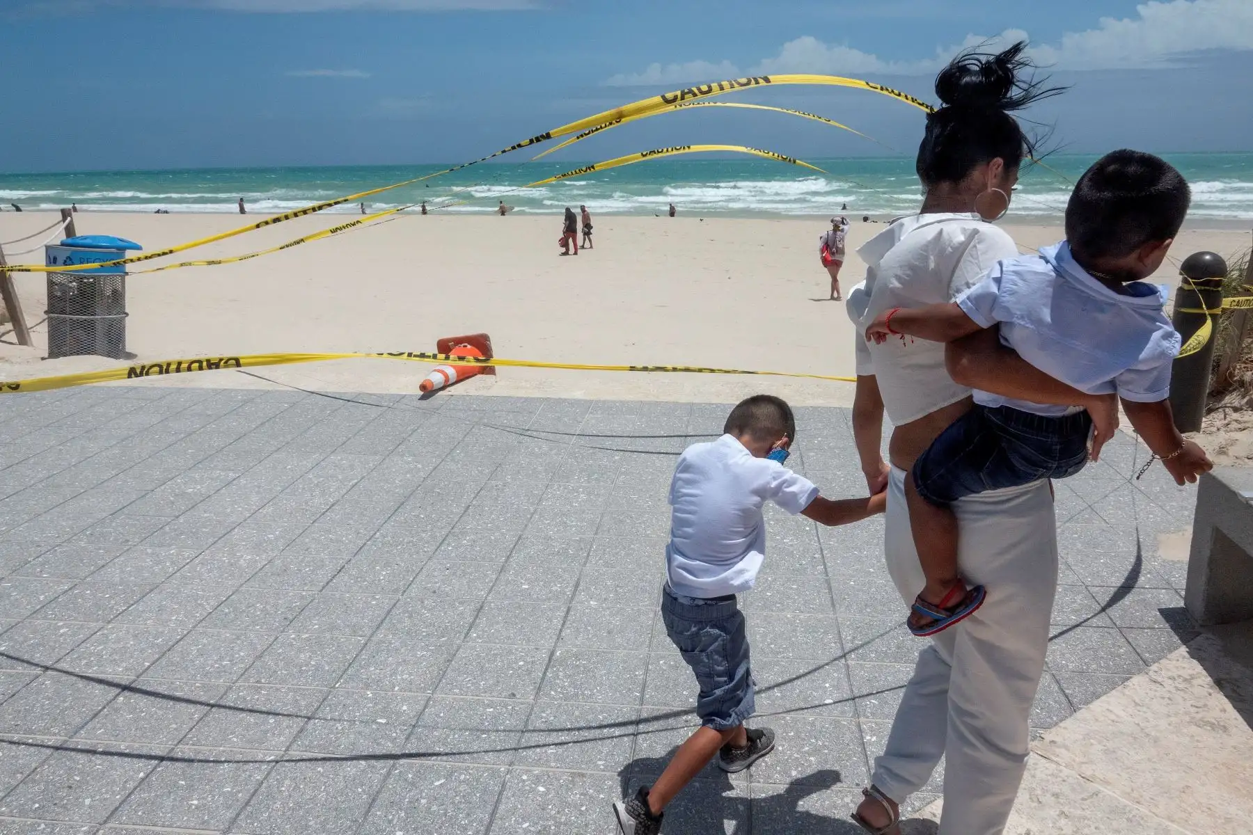 Una mujer camina junto a sus hijos por las playas de Miami, Florida, ante la pronta llegada del huracán Isaías. Foto: EFE
