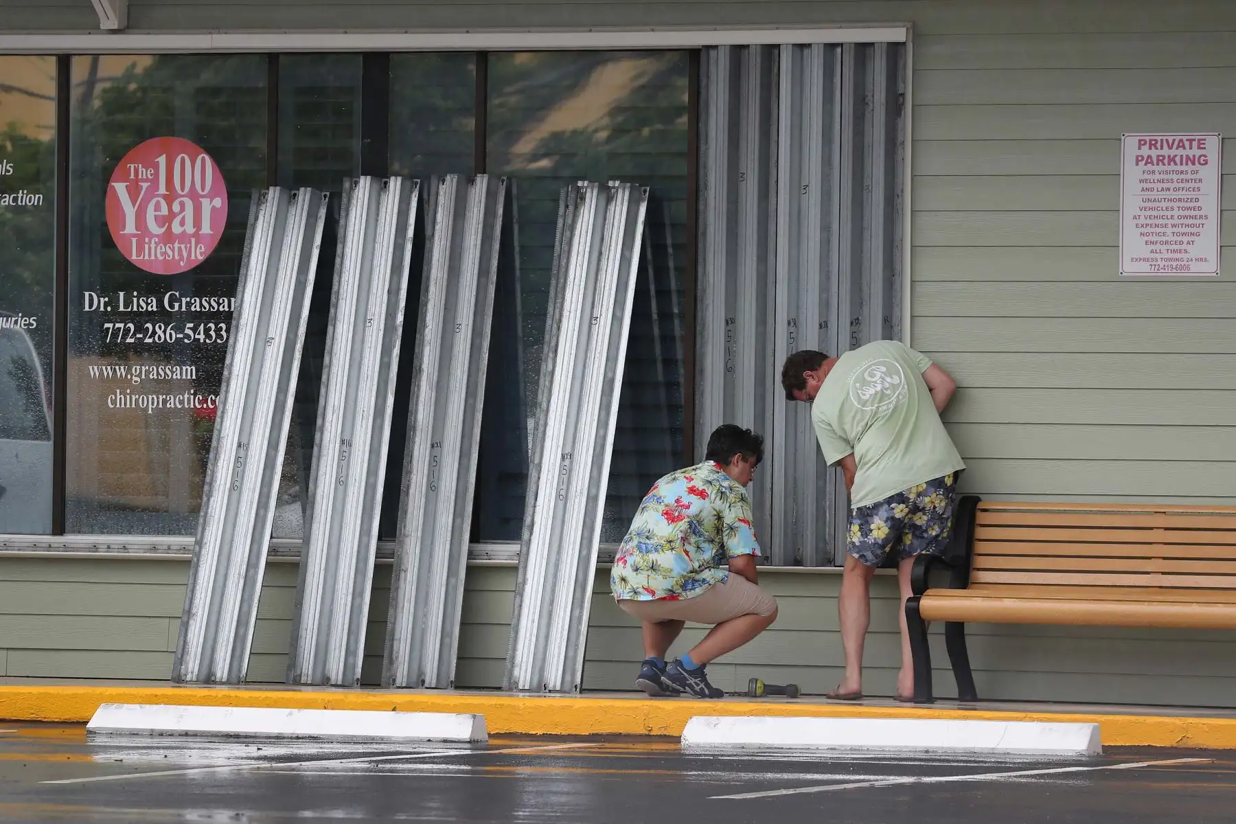 Dos hombres protegen las ventanas de sus negocios a medida que se acerca la el huracán Isaias. Foto: AFP