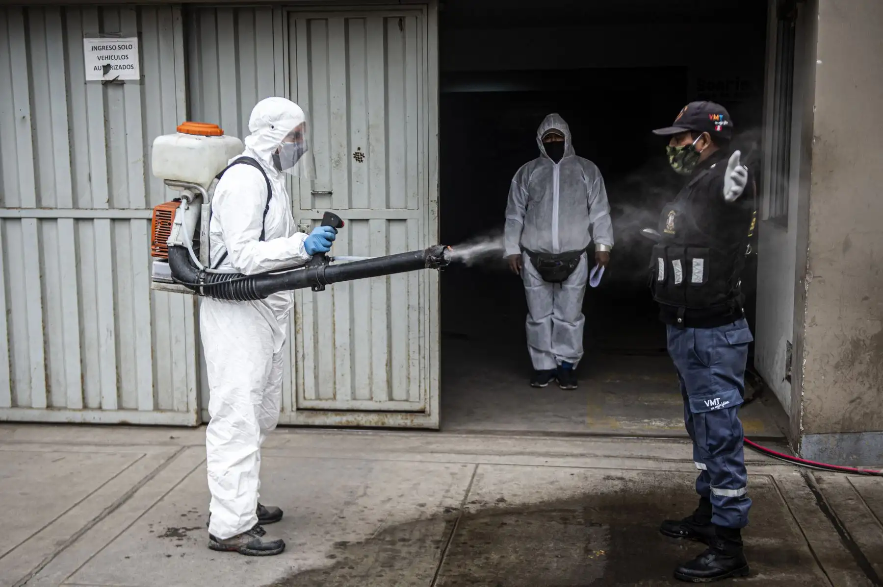 Un trabajador municipal desinfecta a un guardia de seguridad en Villa María del Triunfo. Foto: AFP