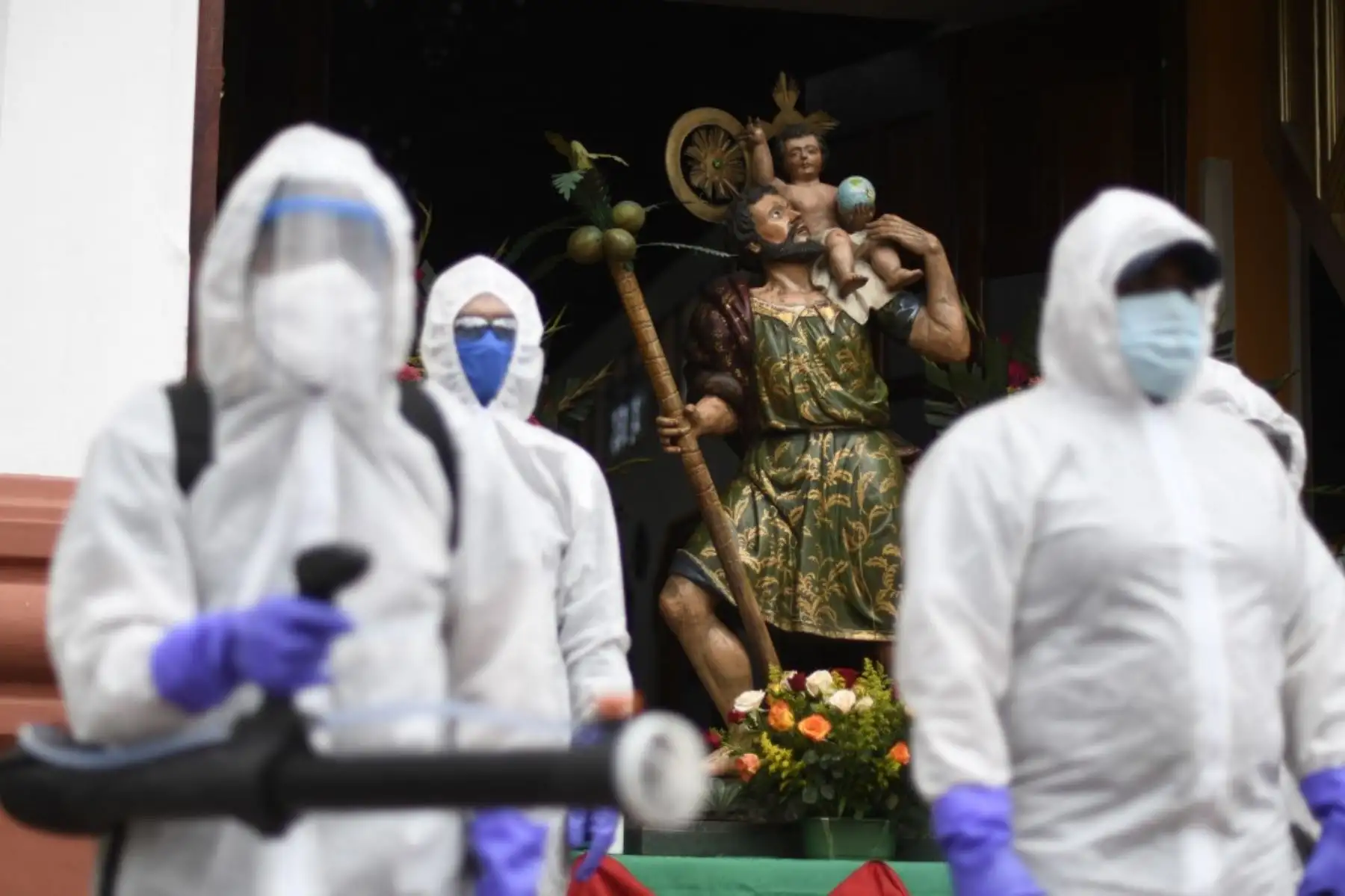 Los trabajadores municipales en traje de protección se preparan para desinfectar un automóvil fuera de una iglesia durante la celebración del Día de San Cristóbal, patrón de viajeros y conductores, en la Ciudad de Guatemala. Foto: AFP
