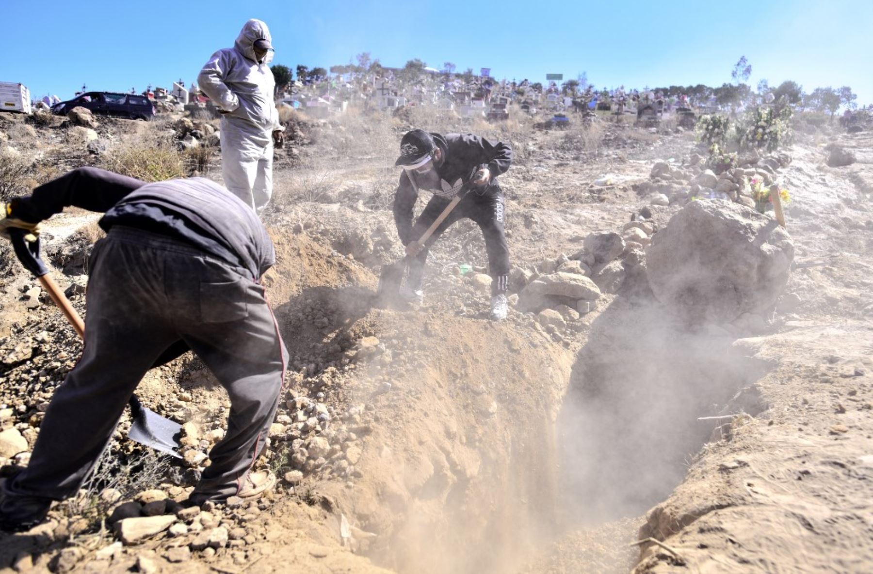 Un grupo de personas entierran a un pariente en una trinchera excavada para las víctimas de covid-19 en el cementerio  El Cebollar de bajo costo en el distrito rural de Paucarpata, cerca de la ciudad de Arequipa, Perú. Foto: AFP