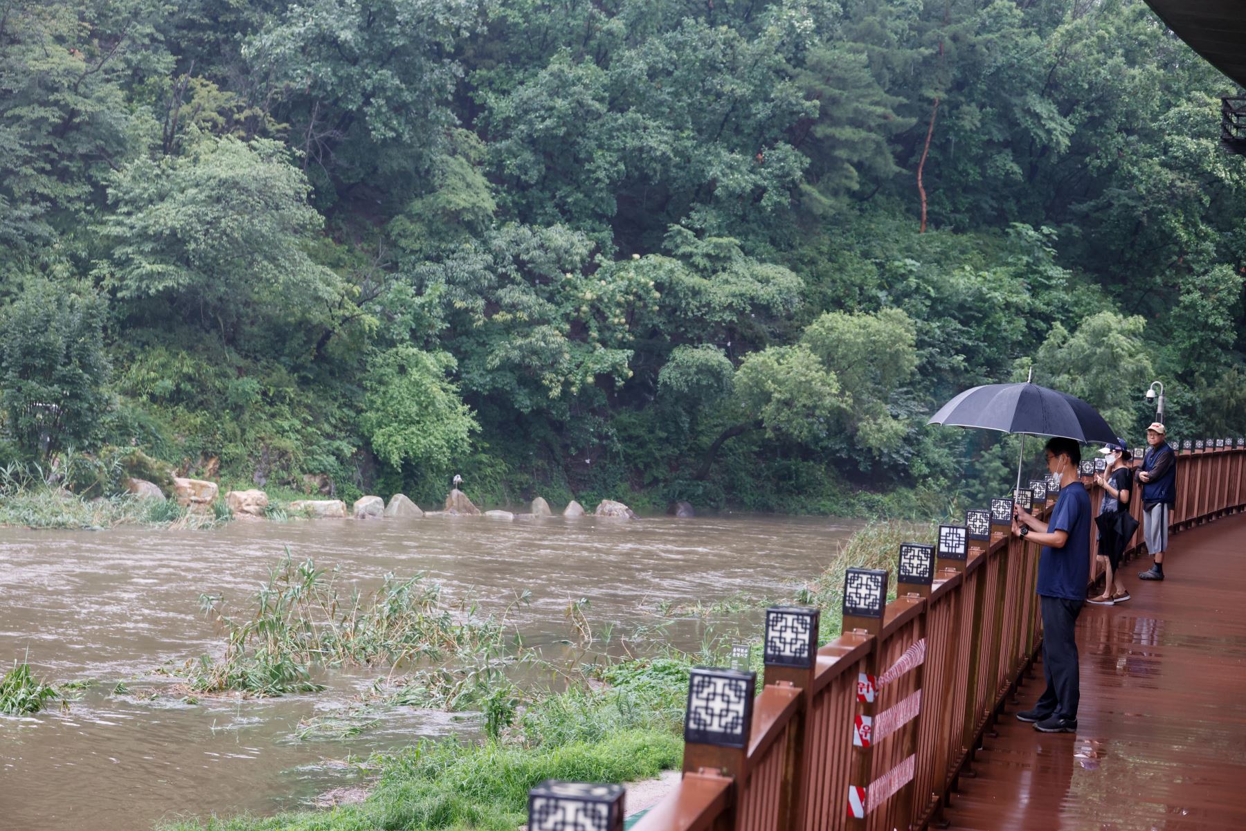 La gente mira un parque inundado a lo largo del arroyo Hongje en Seúl, Corea del Sur. Según informes de prensa, 13 personas están muertas y 13 personas faltan después de fuertes lluvias que causaron inundaciones en Seúl. 

Foto: EFE