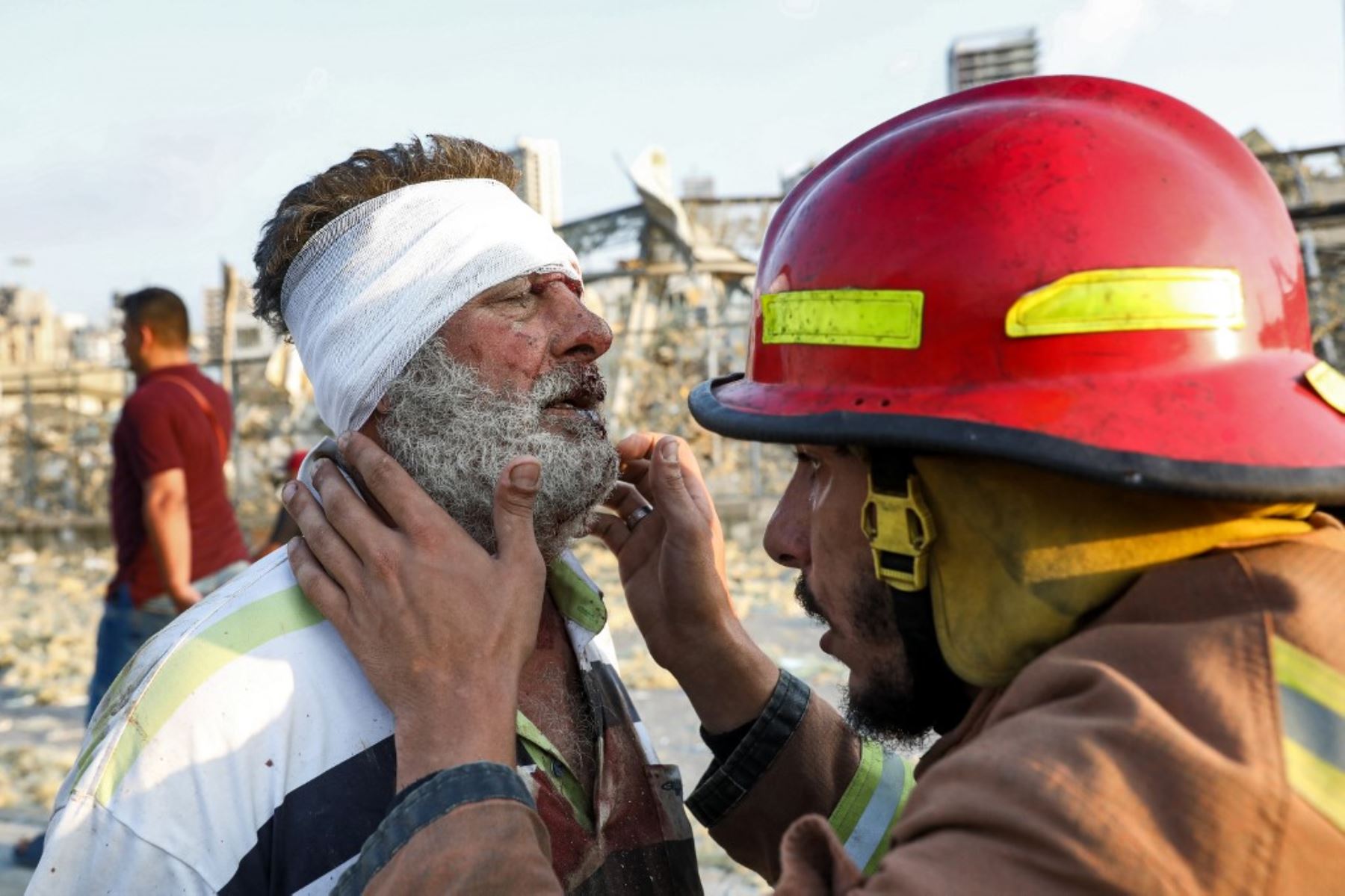 Un bombero controla a un hombre herido cerca de la escena de una explosión en Beirut el 4 de agosto de 2020. Foto: AFP