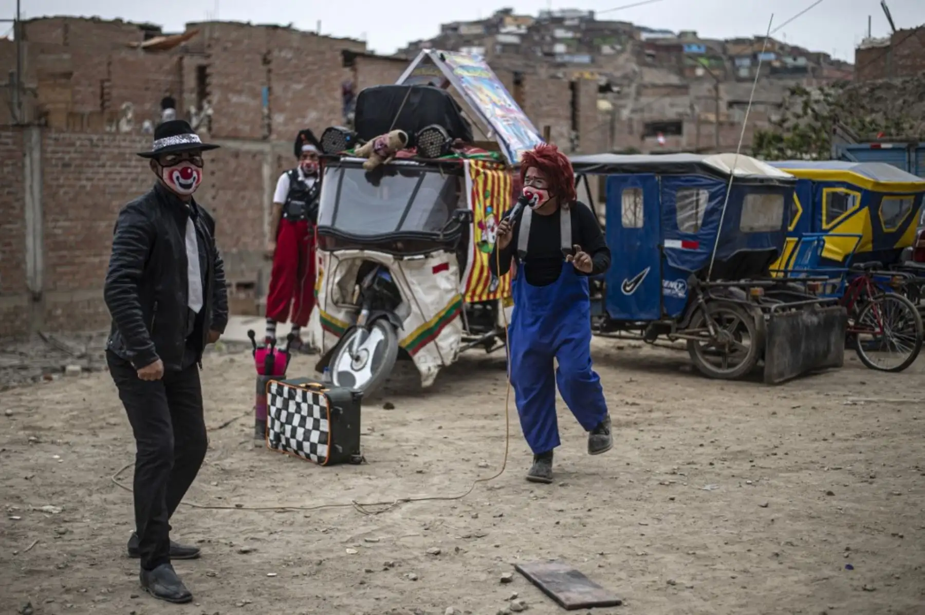 Los payasos con máscaras se presentan en el distrito de Puente Piedra, en las afueras del norte de Lima, durante la pandemia covid-19. Debido a la pandemia de coronavirus, los circos en Perú permanecen cerrados, lo que lleva a este grupo de payasos que viajan en su circo mototaxi a actuar en las calles de Lima. 

Foto: AFP