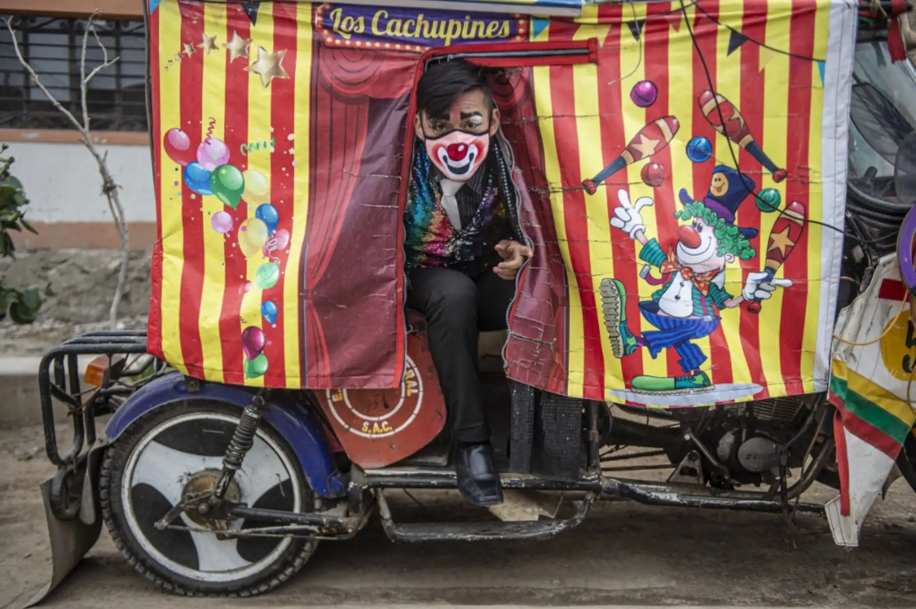 Los payasos con máscaras se presentan en el distrito de Puente Piedra, en las afueras del norte de Lima, durante la pandemia covid-19. - Debido a la pandemia de coronavirus, los circos en Perú permanecen cerrados, lo que lleva a este grupo de payasos que viajan en su circo mototaxi a actuar en las calles de Lima. 

Foto: AFP