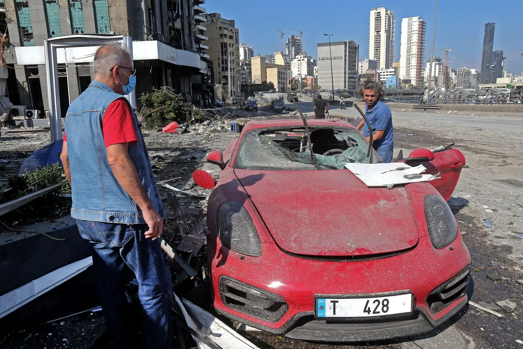 Personas verifican autos y propiedades dañadas a un día de la enorme explosión en el puerto de Beirut. Foto: AFP