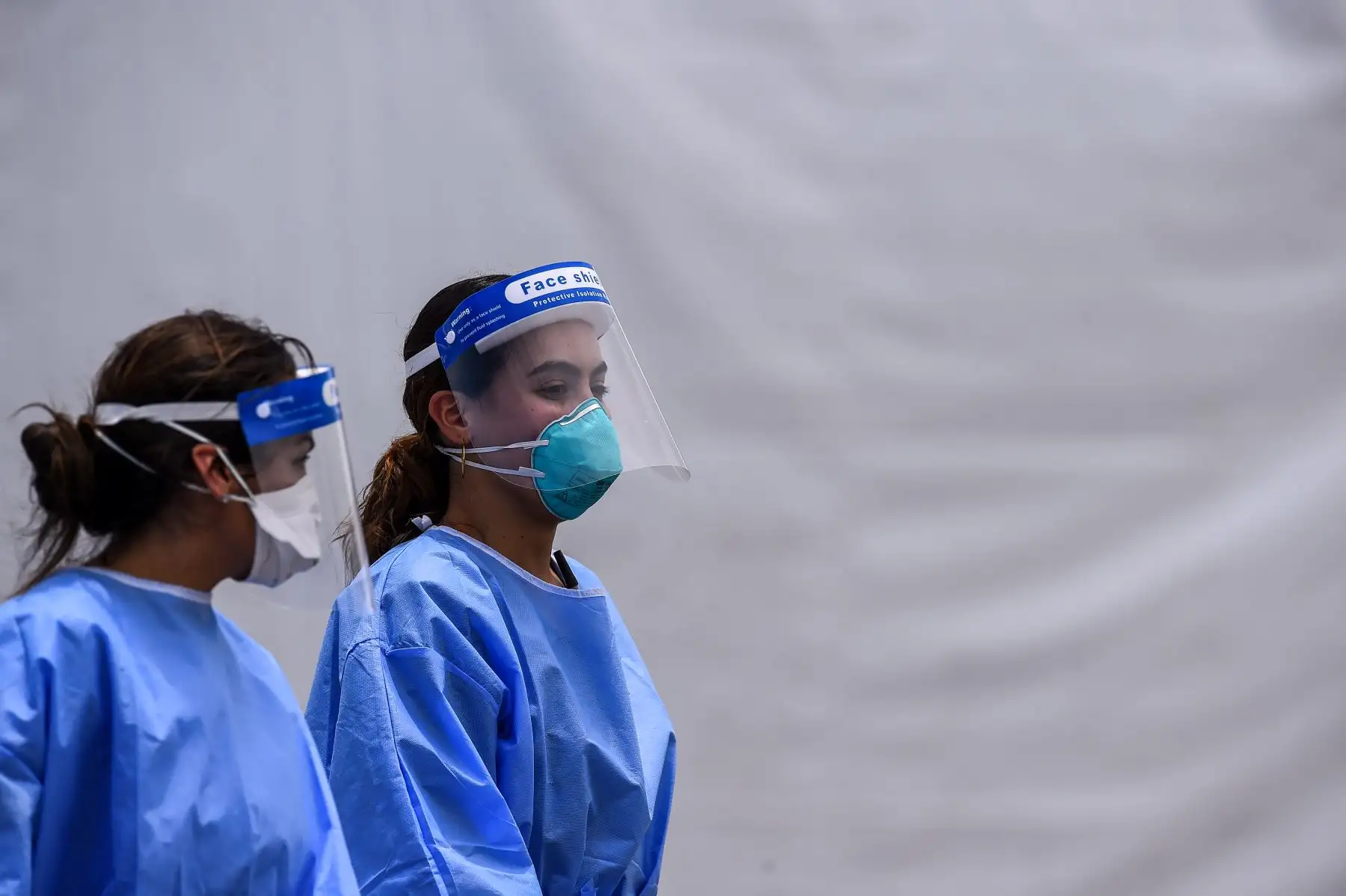 El personal médico usa kits de equipo de protección personal (EPP), que incluyen máscaras faciales y escudos, mientras caminan cerca del sitio de prueba rápida de antígeno del coronavirus en el Hard Rock Stadium en Miami.
Foto: AFP
