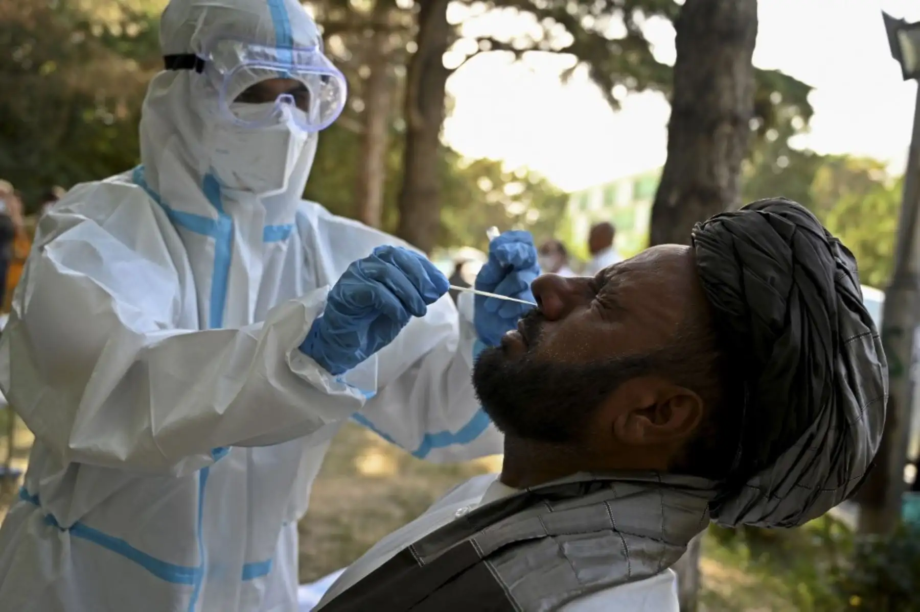 Un funcionario médico que usa un traje de equipo de protección personal toma una muestra de hisopo de un miembro de la Loya jirga (gran asamblea de ancianos afganos) para analizar el coronavirus covid-19 en la Universidad Politécnica de Kabul, Agfanistán. Foto: AFP