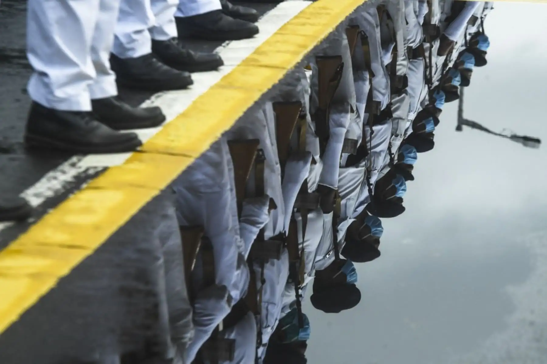 Los oficiales del departamento de policía del estado que llevan máscaras faciales se reflejan en un charco mientras participan en un ensayo antes del próximo desfile del Día de la Independencia en Calcuta. Foto: AFP