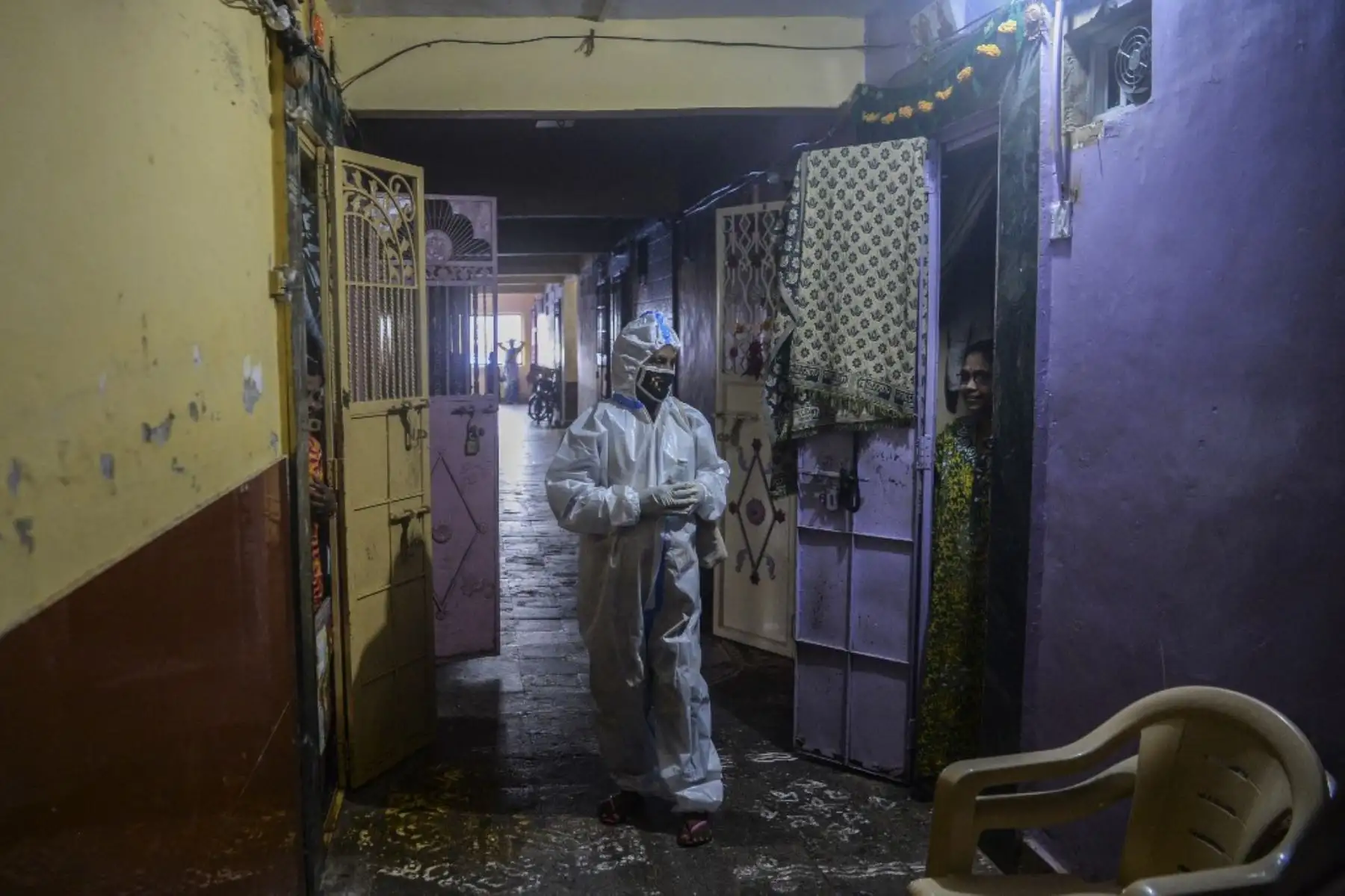 Un trabajador de la salud que usa un traje de Equipo de Protección Personal interactúa con un residente durante un examen de coronavirus covid-19 puerta a puerta en el área de los barrios marginales de Dharavi en Mumbai. Foto: AFP