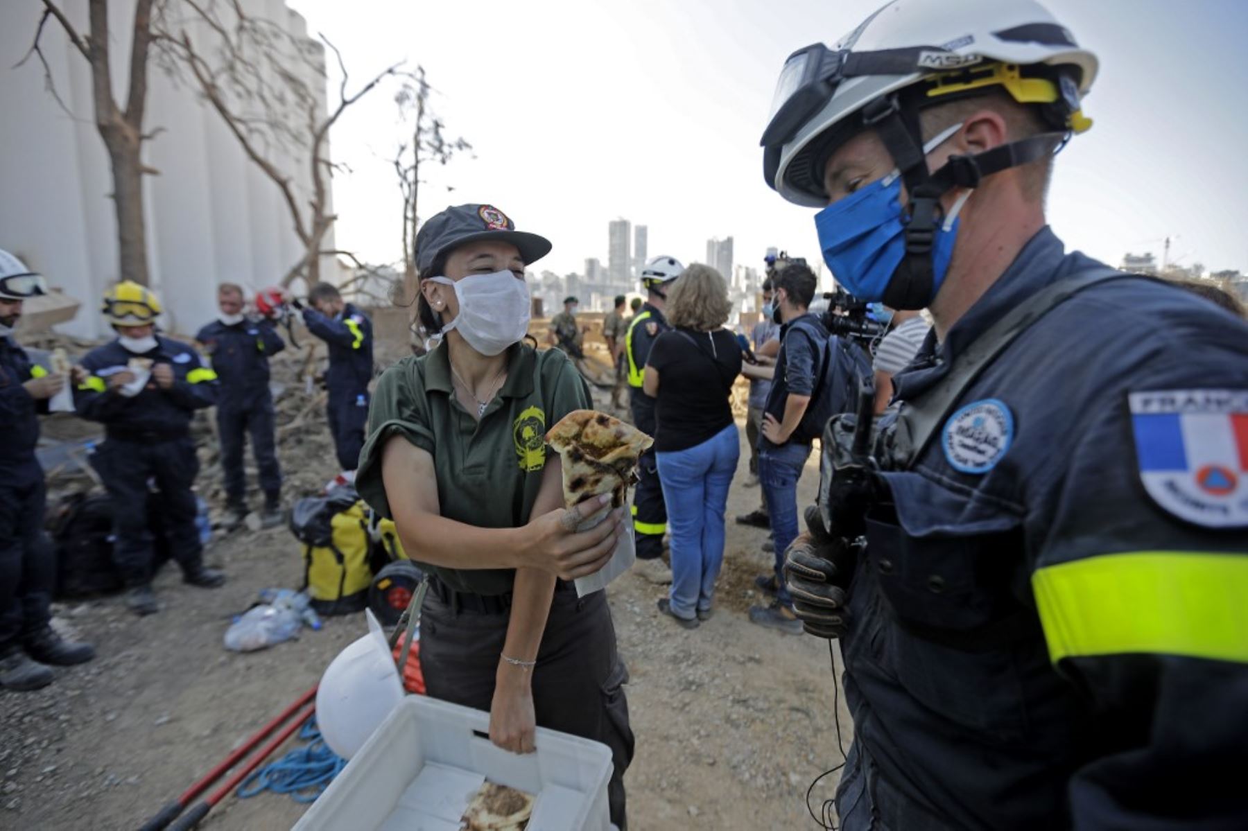 Un rescatador de la defensa civil libanesa ofrece comida a un rescatista francés durante un esfuerzo de búsqueda en el puerto de Beirut. Foto: AFP