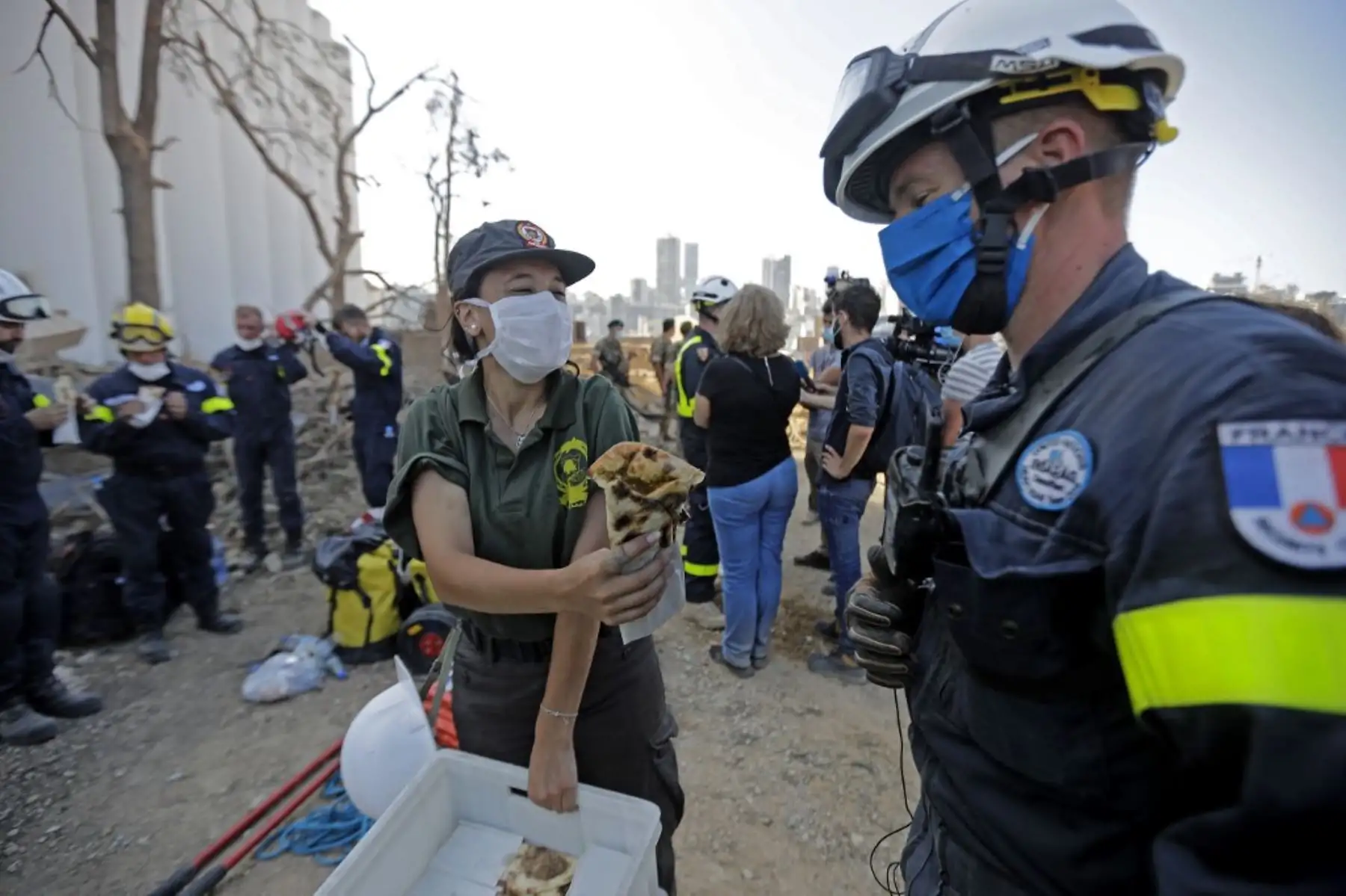 Un rescatador de la defensa civil libanesa ofrece comida a un rescatista francés durante un esfuerzo de búsqueda en el puerto de Beirut. Foto: AFP