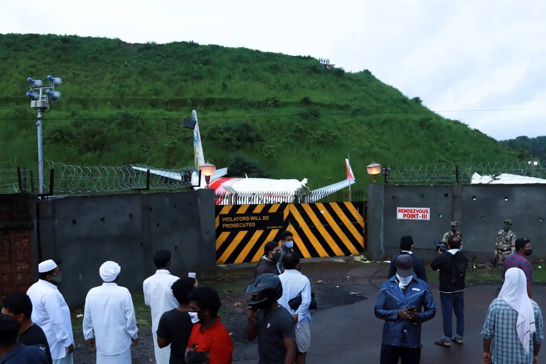 La gente se reúne frente a la puerta donde se encuentras los restos del Air India Express en el Aeropuerto Internacional de Calicut en Karipur, Kerala. Foto: AFP