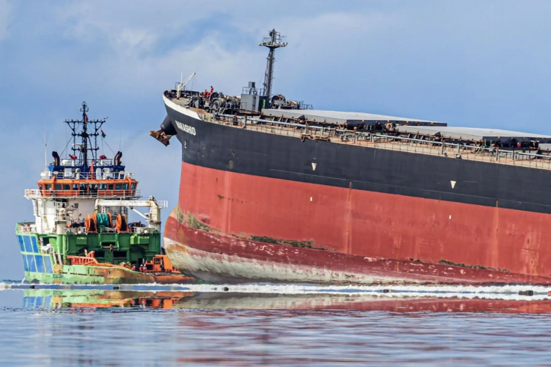 Trabajadores miran desde un barco hacia el buque MV F. responsable del derrame de petróleo. Foto: AFP