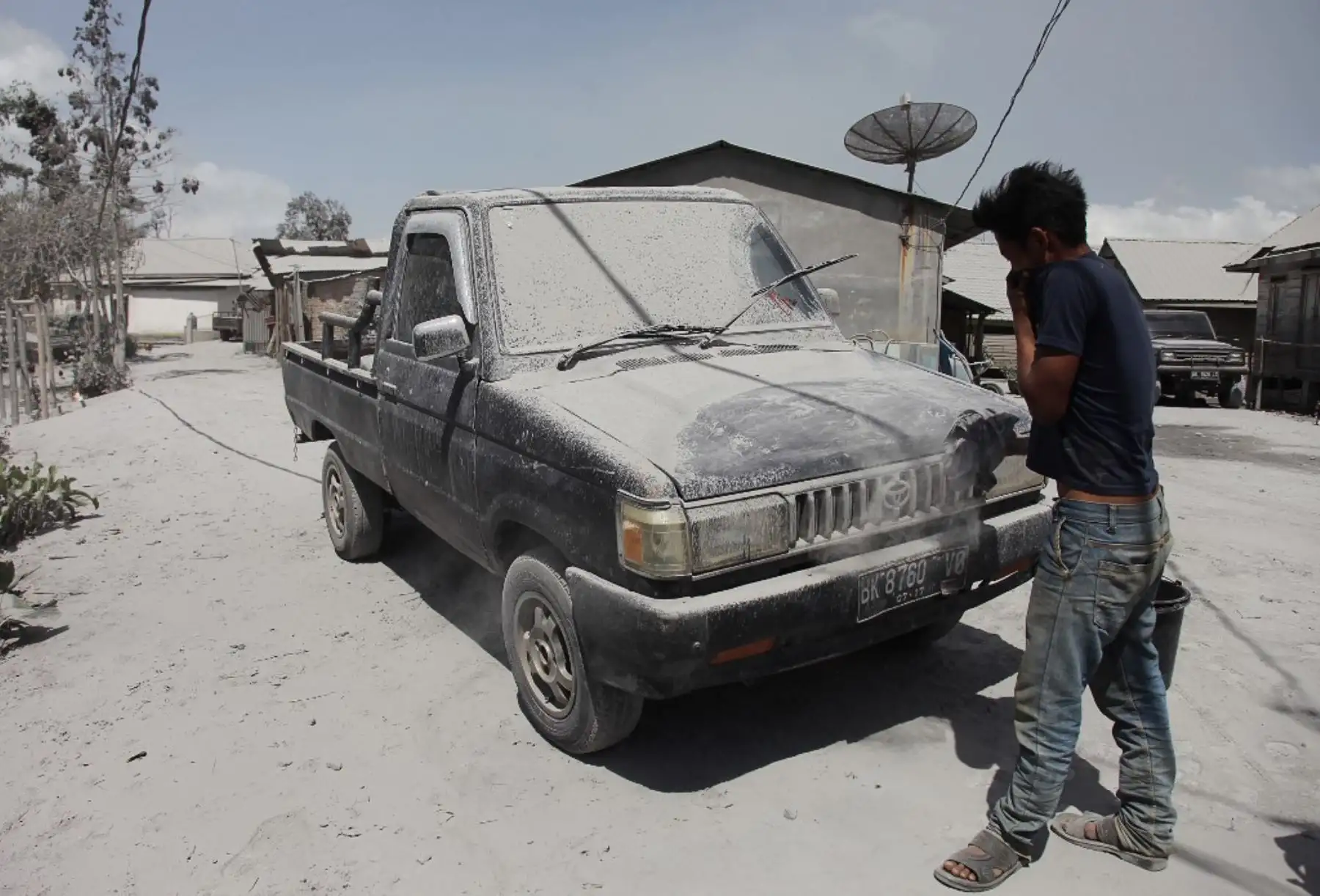 Un hombre limpia un automóvil cubierto de cenizas después de una erupción en el monte Sinabung en la aldea de Sukatepu en Karo, en el norte de Sumatra. Foto: AFP