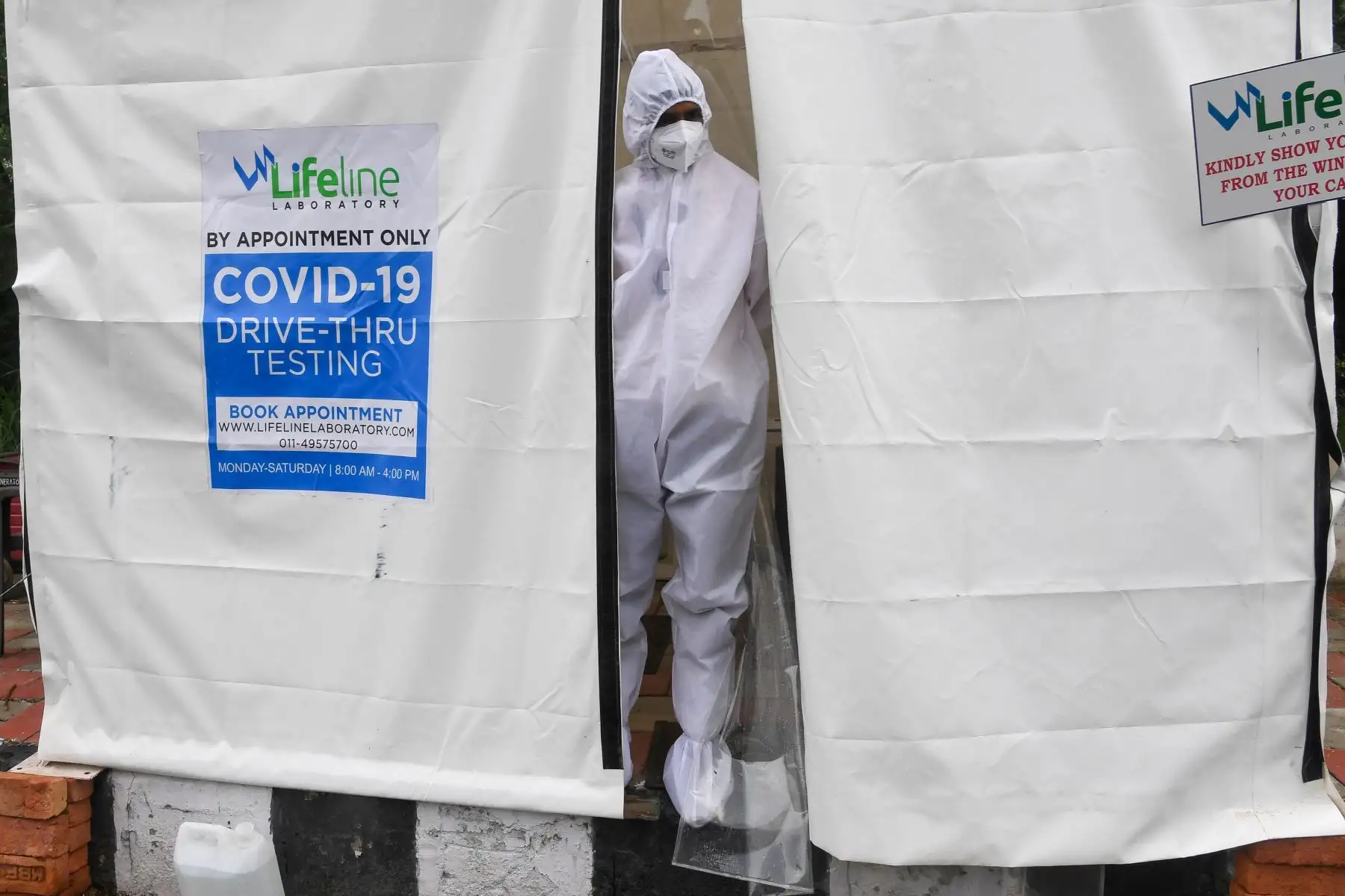 Un trabajador de la salud se asoma desde una caseta improvisada de pruebas de covid -19 junto a una calle en Nueva Delhi .
Foto: AFP