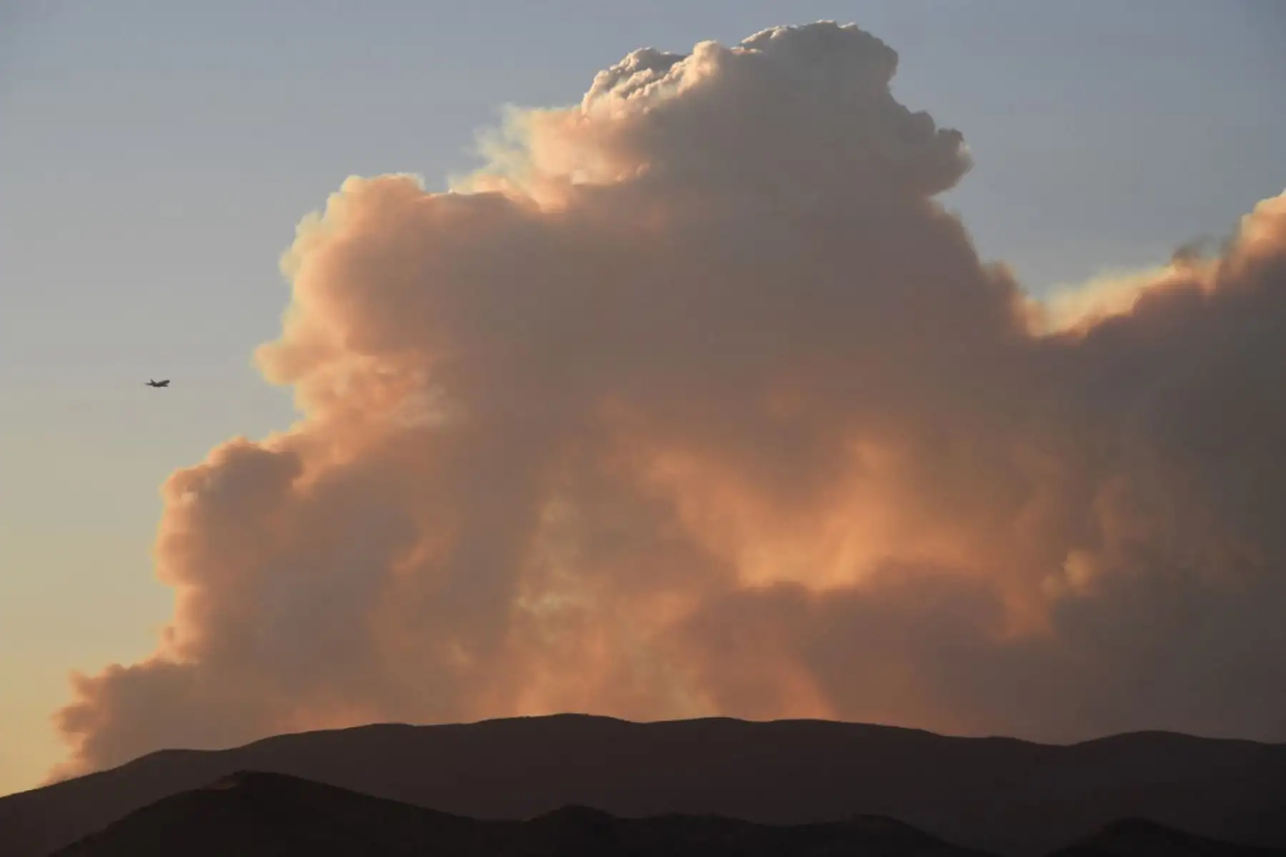 Un avión vuela por la columna de humo del Lake Fire en el Bosque Nacional Ángeles. Foto: AFP