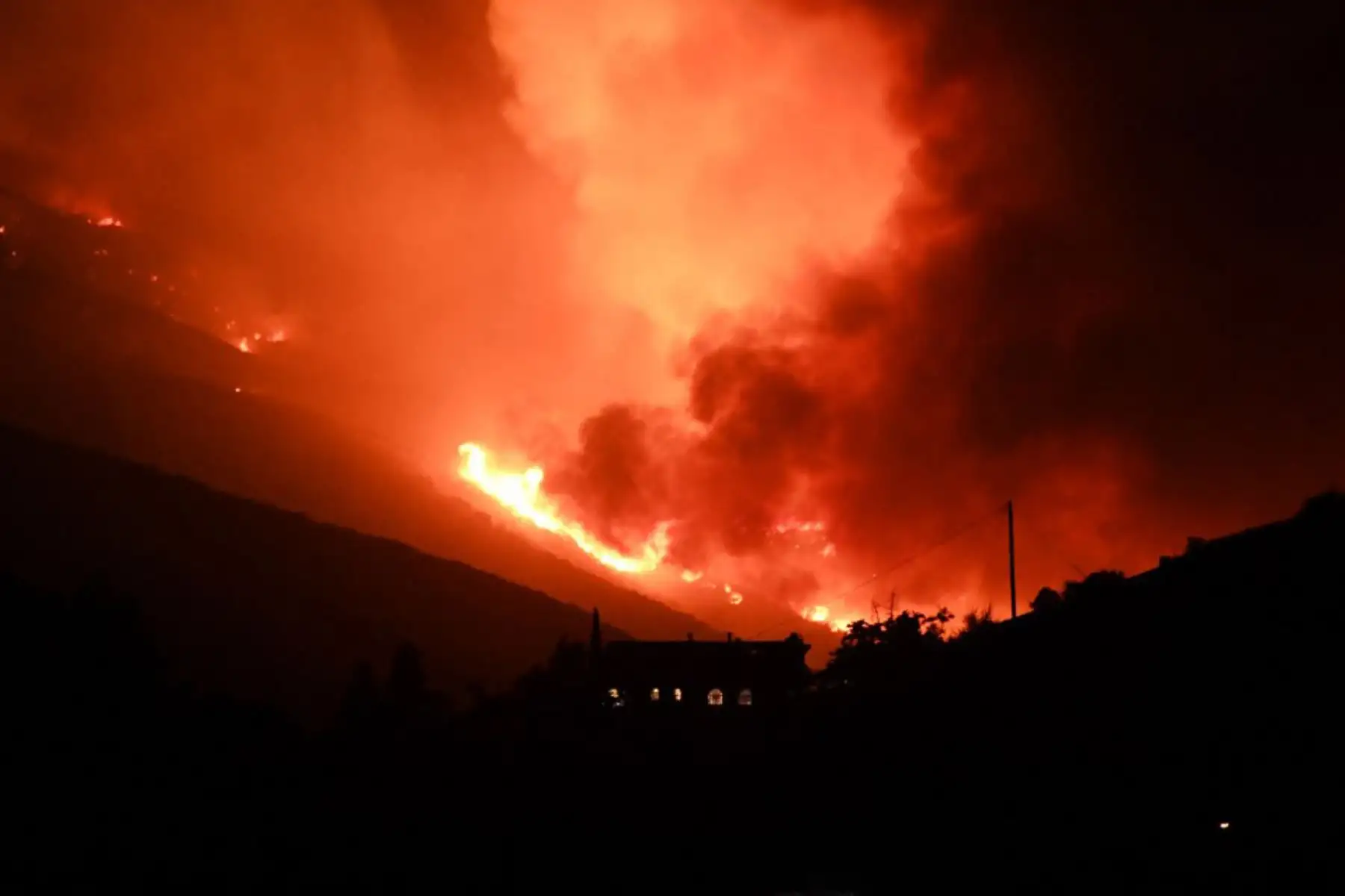 Se ve una casa en la ladera de una colina mientras las llamas del lago Fire arden peligrosamente cerca, en el Bosque Nacional Ángeles. Foto: AFP