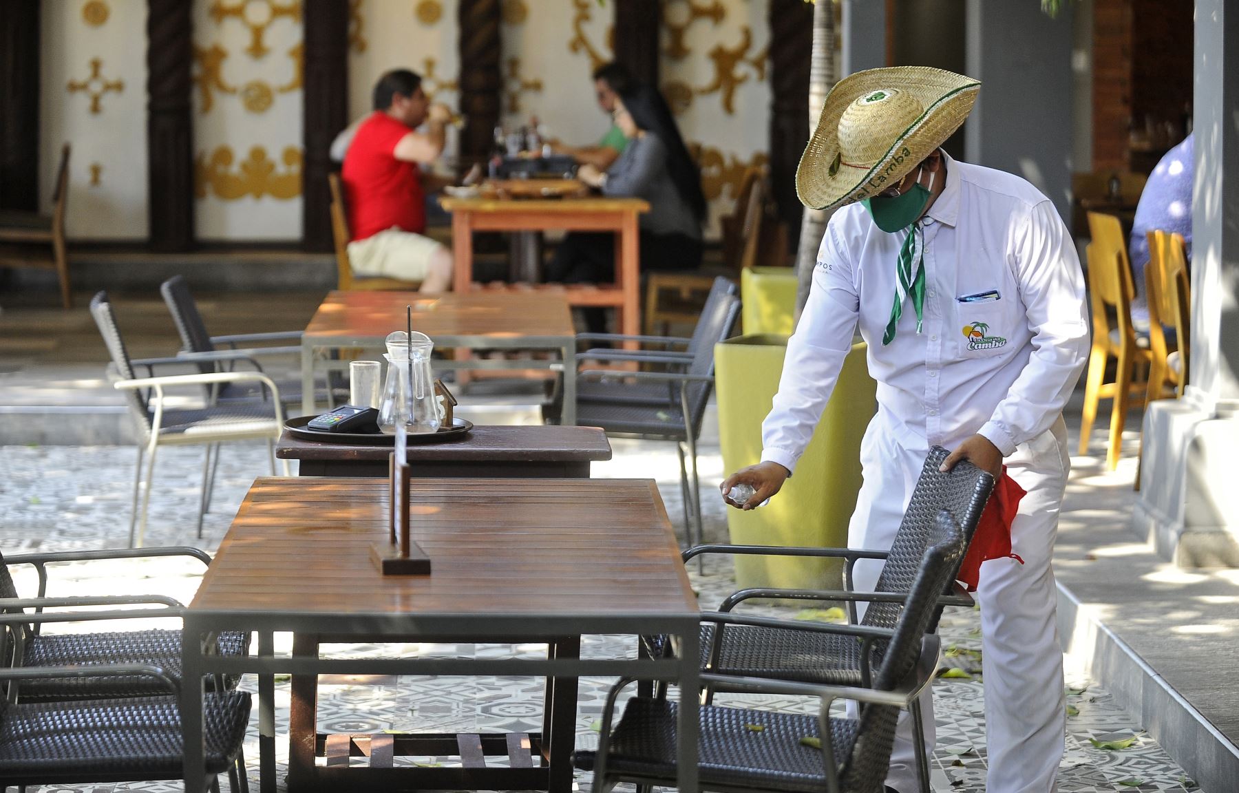 Un camarero desinfecta una mesa en un restaurante de Santa Cruz. La ciudad boliviana comenzó a flexibilizar las restricciones en la lucha contra el nuevo coronavirus. Foto: AFP