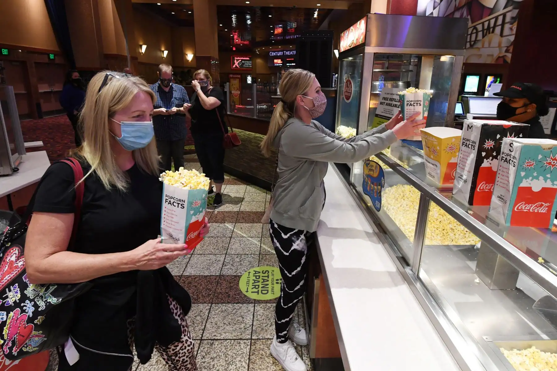 Dos mujeres obtienen palomitas de maíz en un puesto de Cinemark