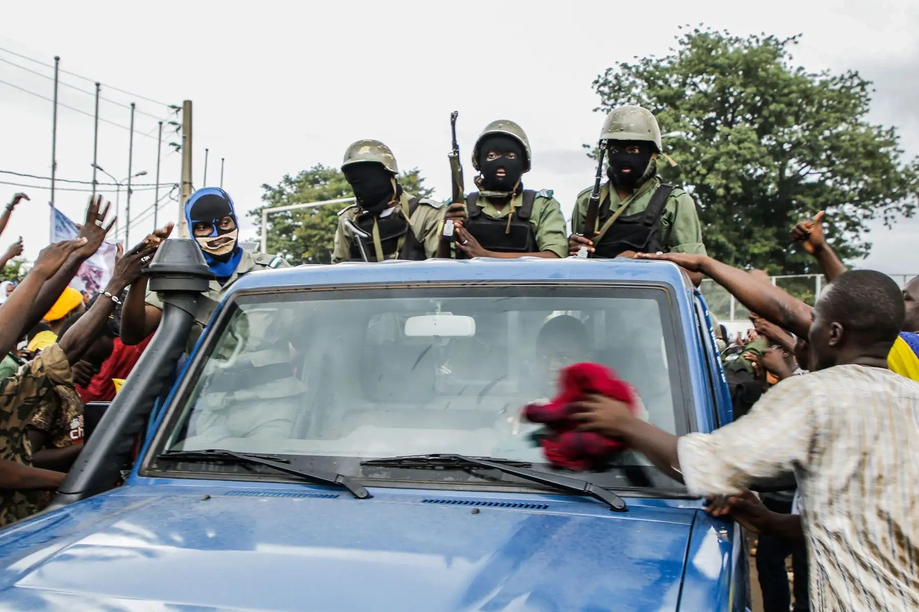 Un hombre utiliza un paño rojo para limpiar el parabrisas de una camioneta que transporta soldados malienses armados y enmascarados cuando llegan a la Plaza de la Independencia en Bamako.
Foto: AFP