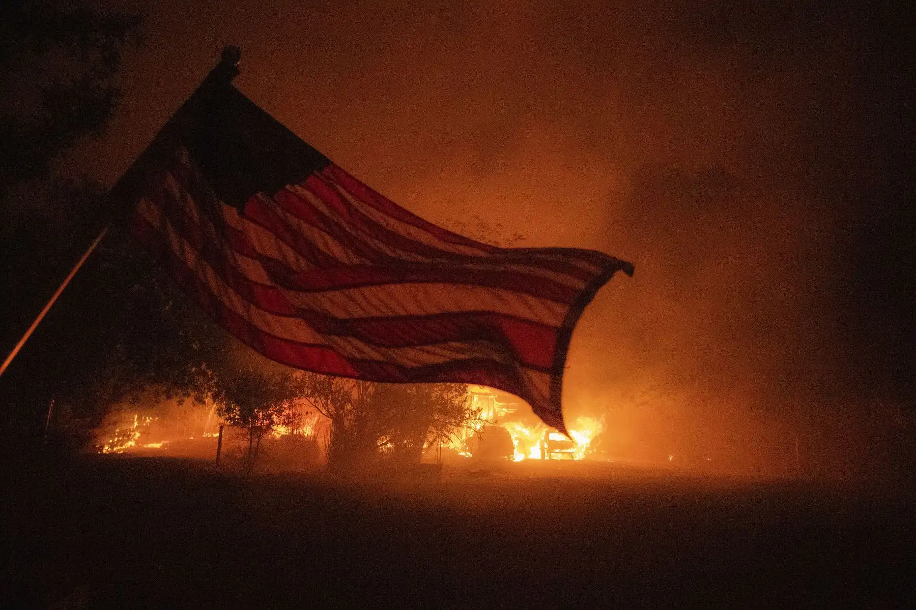 Una bandera estadounidense ondea en el viento frente a una casa en llamas en Vacaville, California, durante el incendio del Complejo Relámpago LNU.
Foto: AFP