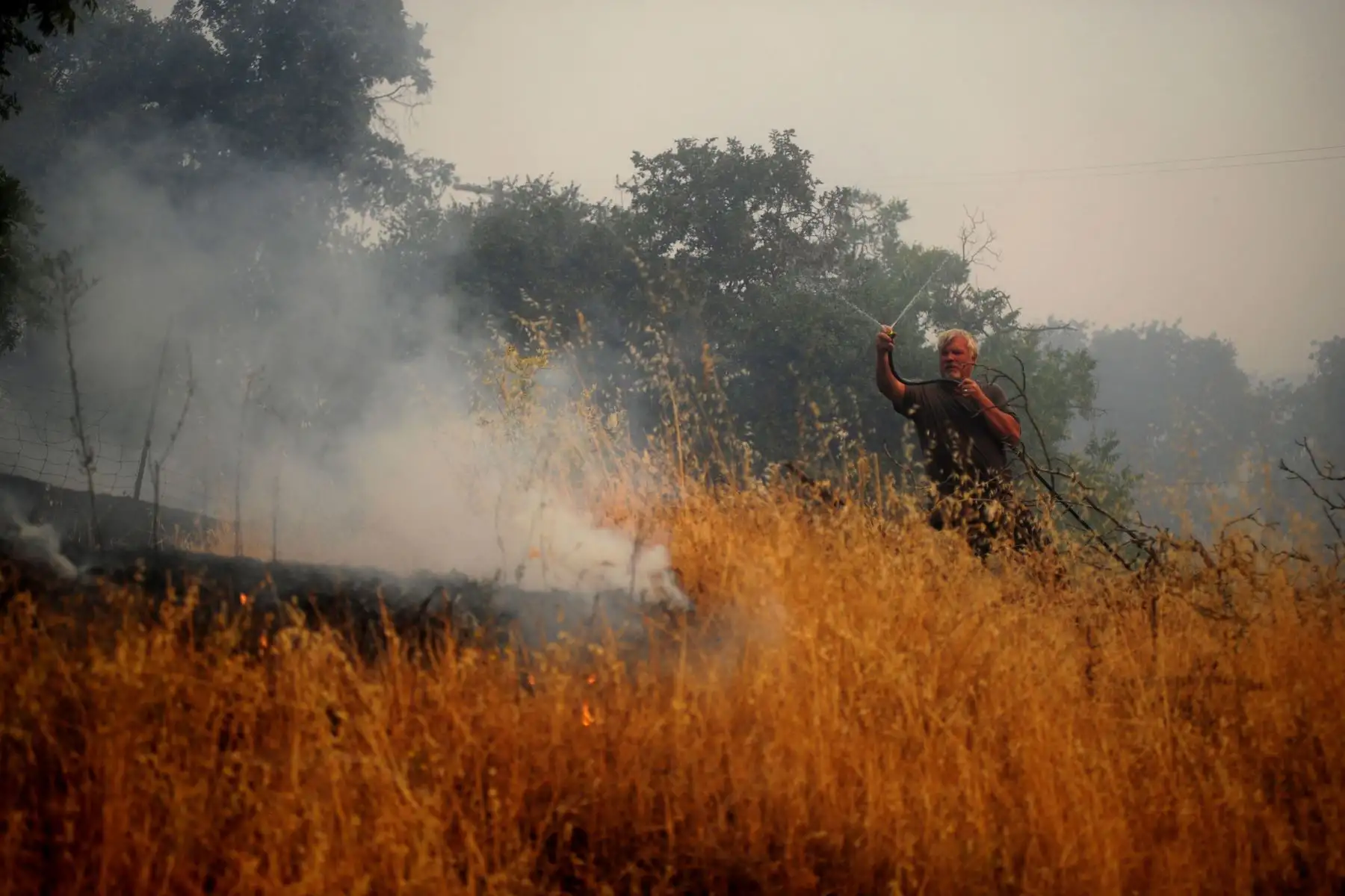 El propietario Dean Lang usa su manguera de jardín para tratar de evitar que el fuego llegue a sus casas y las de sus vecinos cerca de Vacaville, California, EE. UU.
Foto: EFE
