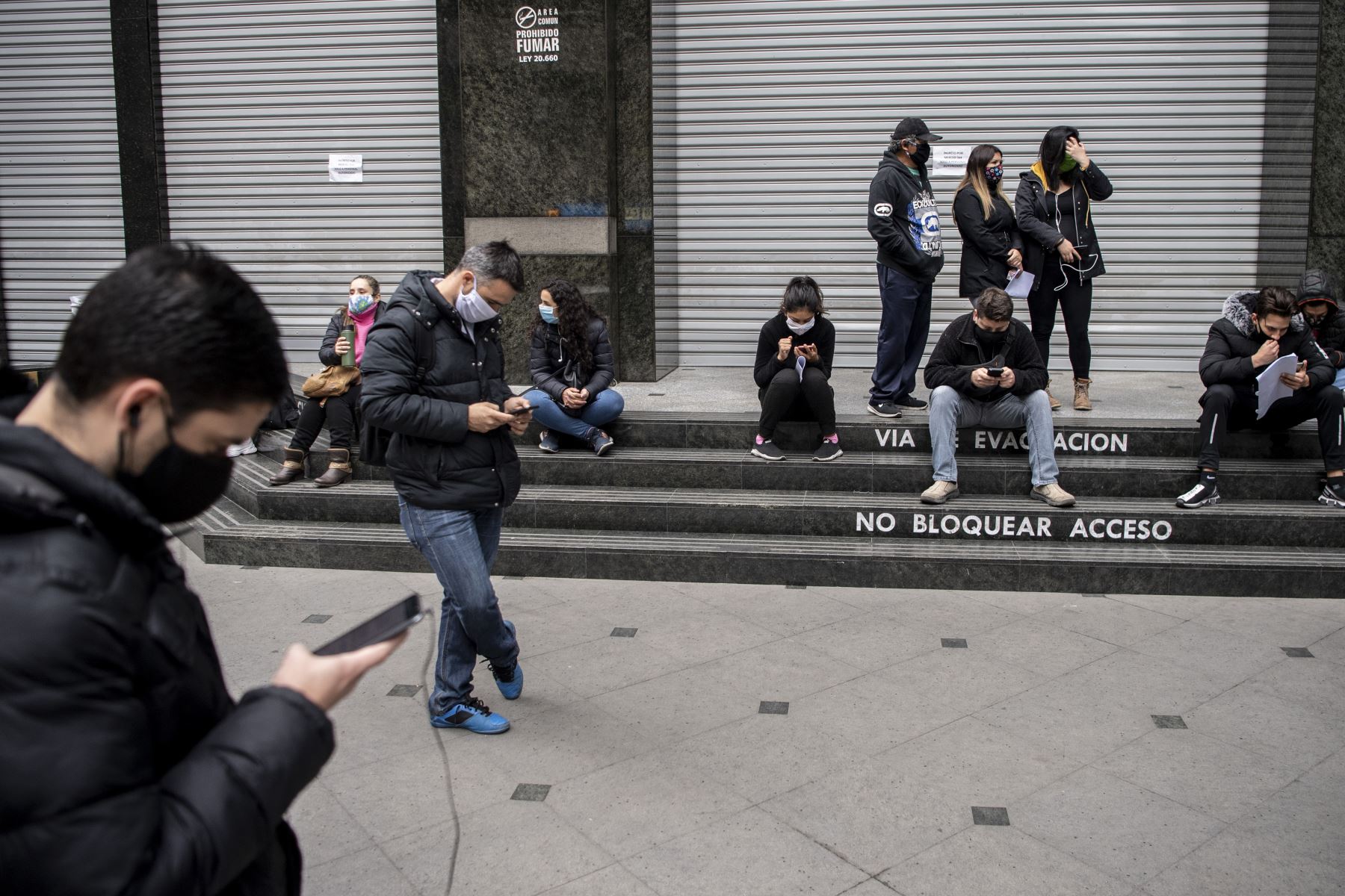 Personas usan mascarillas mientras hacen cola para obtener un seguro de desempleo frente a la sede de la Administración de Fondos de Desempleo de Chile en Santiago. Una crisis económica agravada por el cierre ha dejado a un número significativo de latinoamericanos sin medios de vida. Foto: AFP