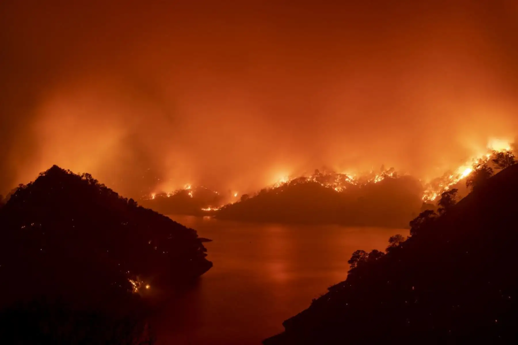 El fuego rodea el lago Berryessa durante el incendio del LNU Lightning Complex en Napa, California. Miles de personas huyeron de sus hogares en el norte de California cuando cientos de incendios forestales de rápido movimiento se extendieron por la región, quemando casas y conduciendo a la muerte de un piloto de helicóptero. 

Foto: AFP