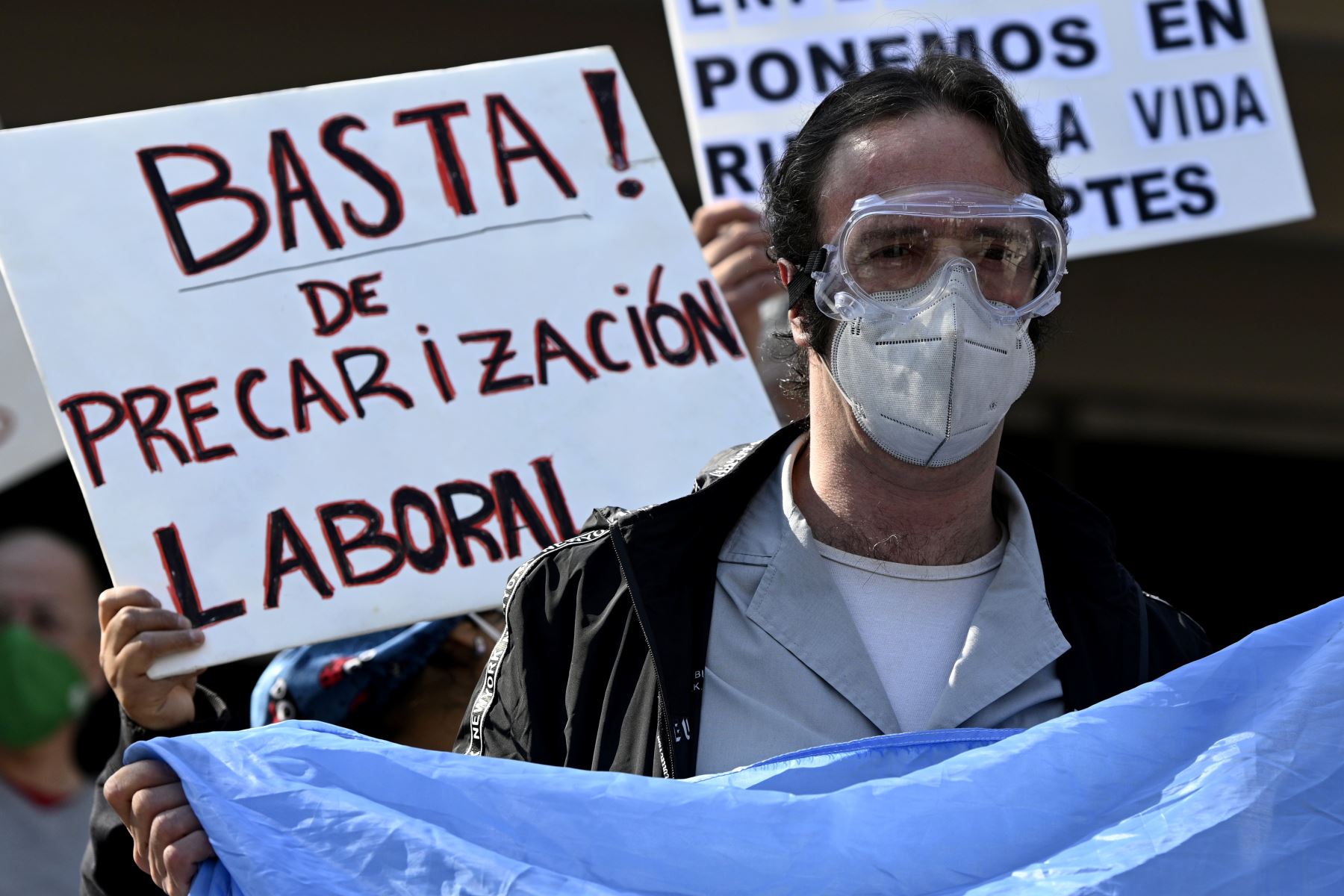 Un trabajador de la salud sostiene una bandera argentina durante una protesta para exigir mejores condiciones laborales y para rendir homenaje a las enfermeras fallecidas por covid-19, frente al hospital Carlos G. Durand de Buenos Aires. Foto: AFP