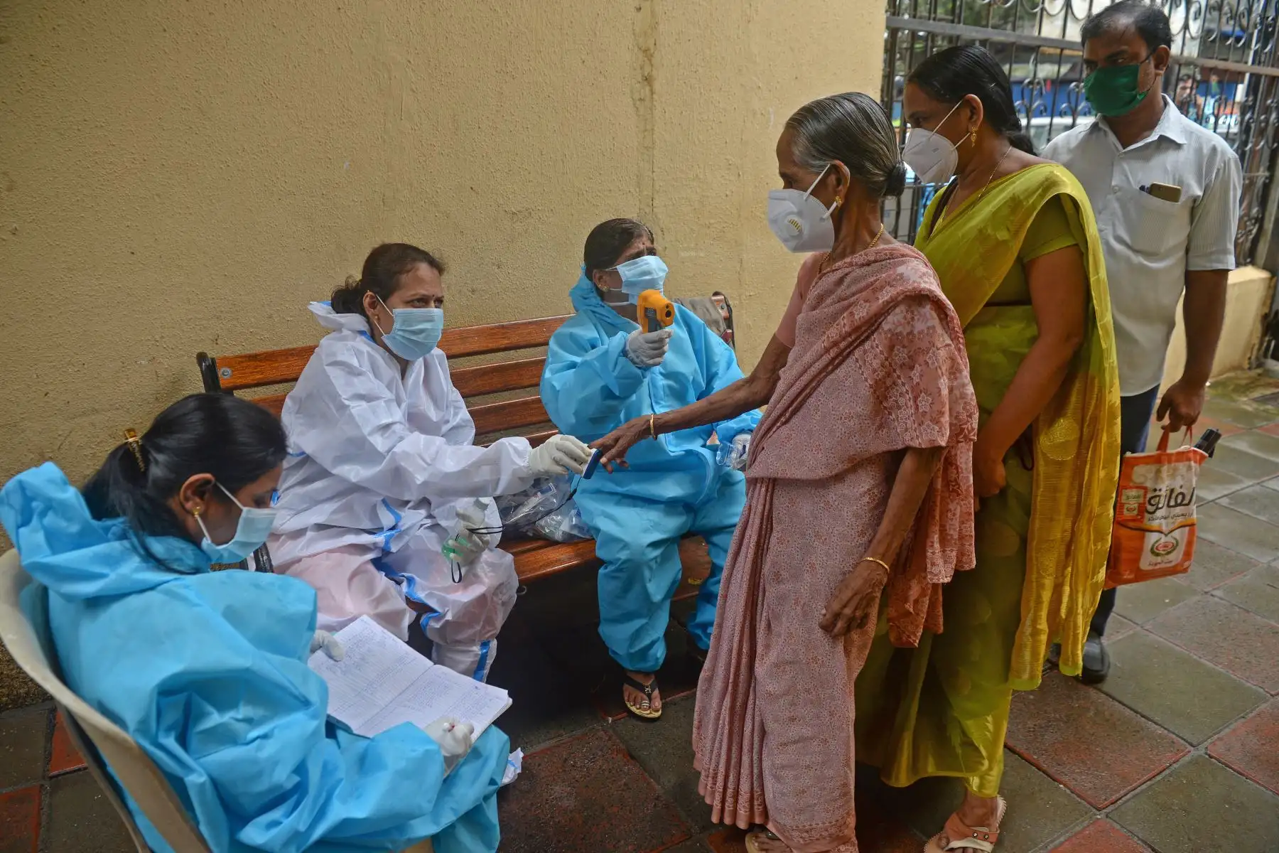 Los trabajadores de la salud controlan el pulso a través del oxímetro y verifican la temperatura corporal de los residentes de los barrios marginales de Dharavi, en Mumbai. Foto: AFP