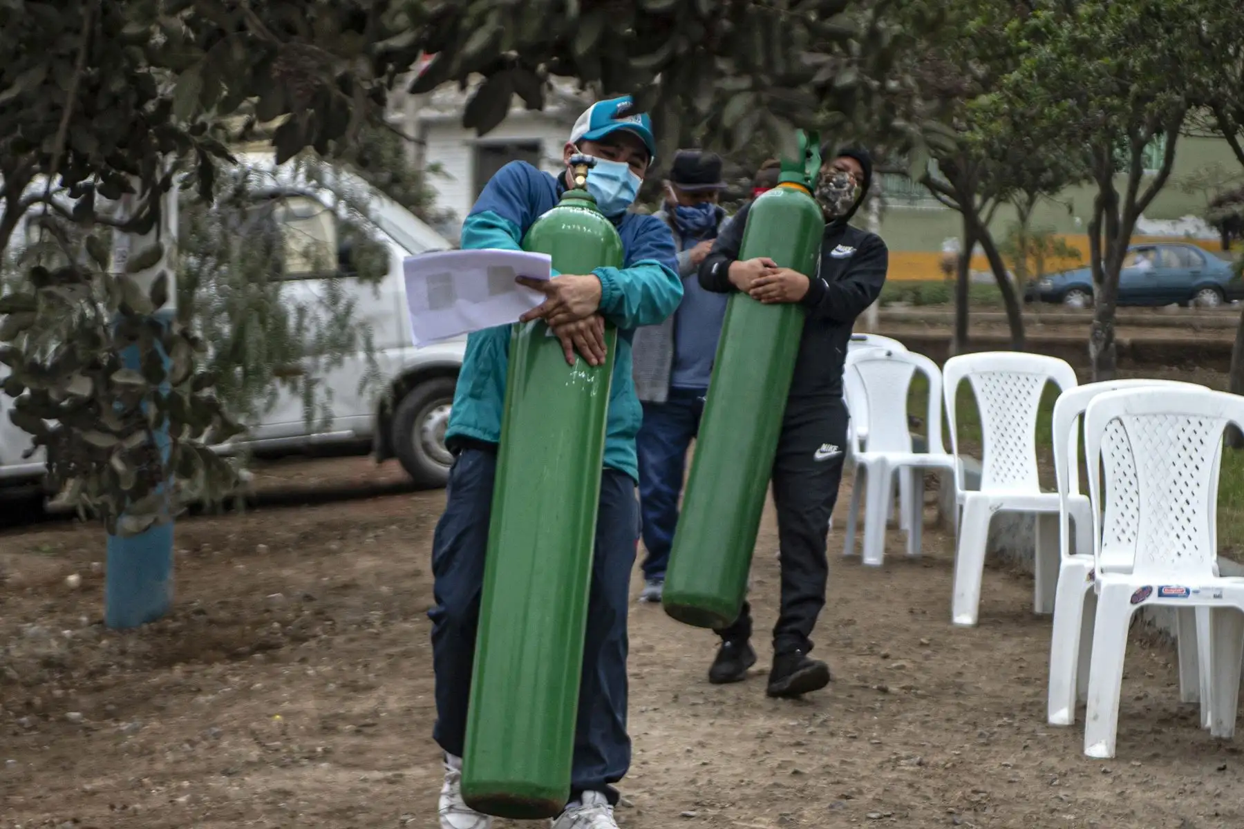 Familiares de pacientes Covid-19 mueven balones de oxígeno mientras hacen cola para recargarlos, en Villa María del Triunfo, Lima. Foto: AFP