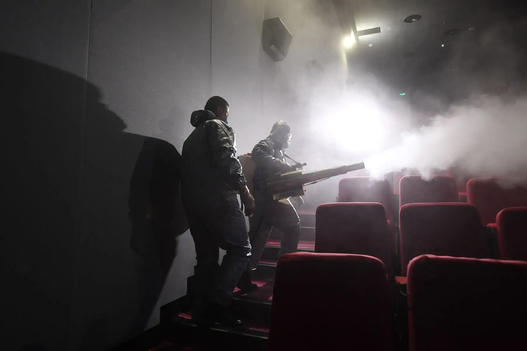 Miembros del equipo de Blue Sky Rescue desinfectan un cine en Beijing antes de su reapertura, en China. Foto: AFP