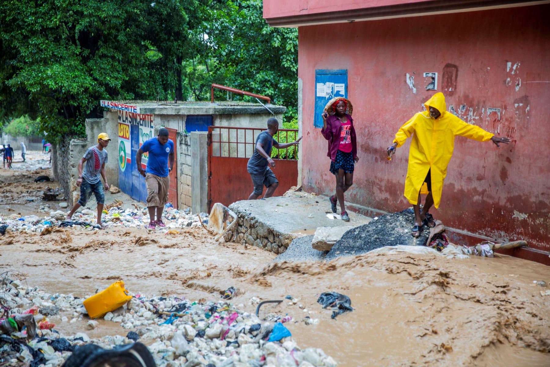 Personas caminan por una calle afectada por las intensas lluvias de la tormenta tropical Laura, este domingo en Puerto Príncipe (Haití). Foto: EFE