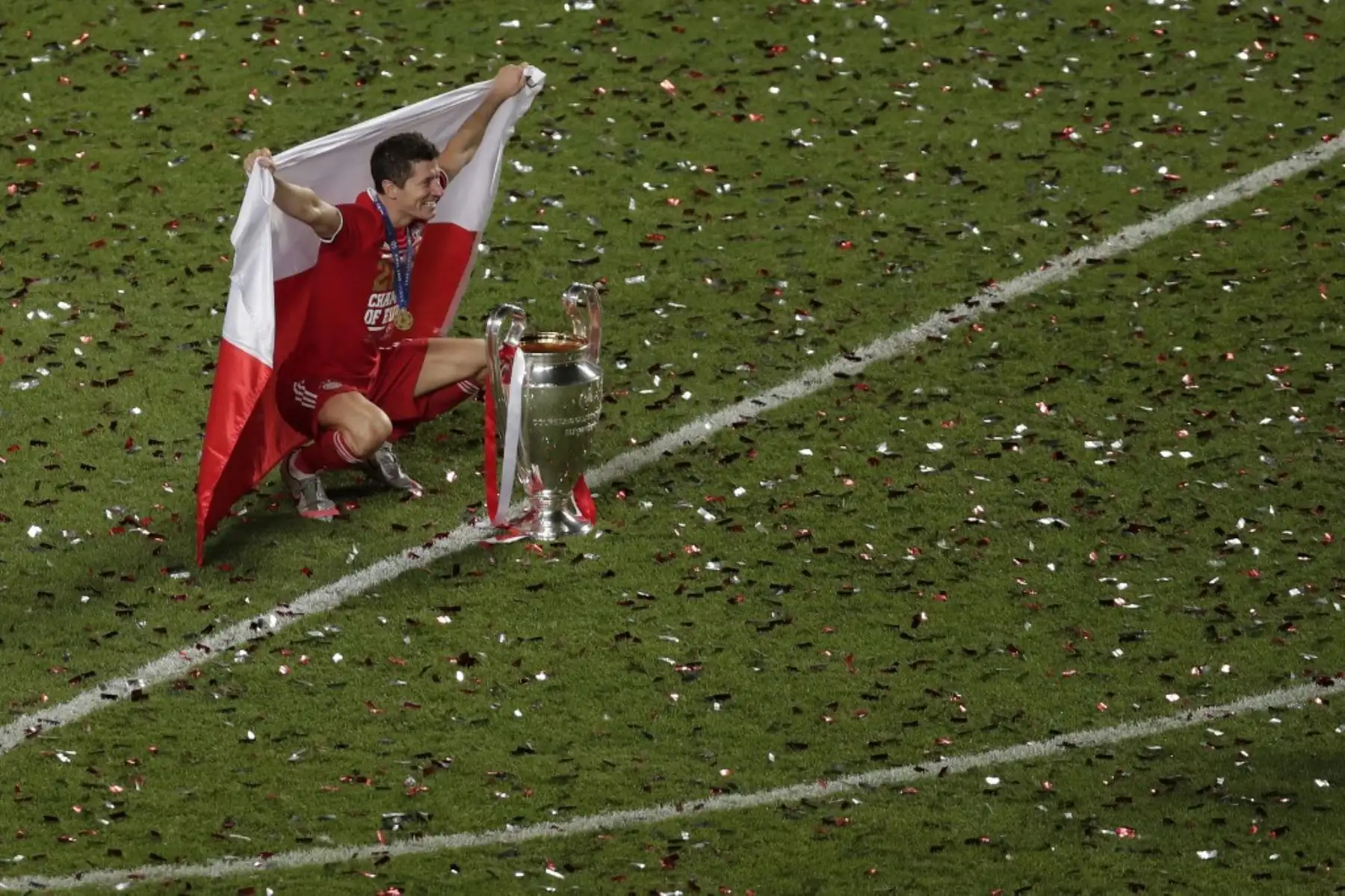 El delantero polaco del Bayern Munich Robert Lewandowski, sosteniendo la bandera polaca, posa con el trofeo después de que el Bayern ganó el partido de fútbol final de la UEFA Champions League entre el Paris Saint-Germain y el Bayern Munich en el estadio Luz de Lisboa. Foto: AFP