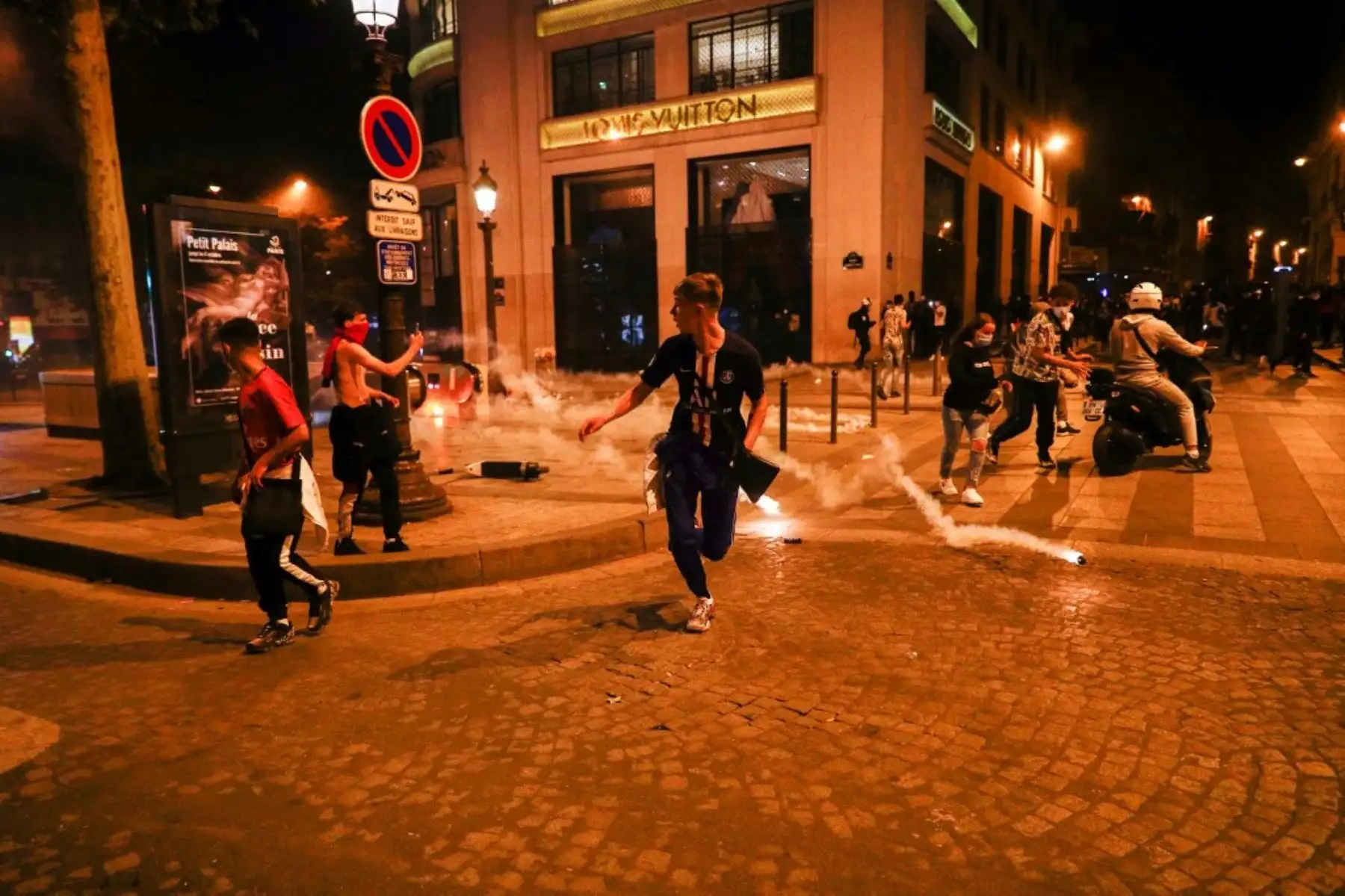 Los seguidores del Paris Saint-Germain (PSG) huyen de los botes de gas lacrimógeno en los Campos Elíseos en París el 23 de agosto de 2020, después del final del partido de fútbol final de la UEFA Champions League contra el Bayern de Múnich jugado en el estadio Luz de Lisboa. Foto: AFP