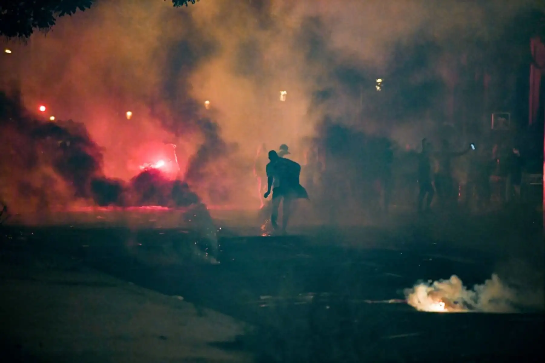 Un hombre se para en humo de gas lacrimógeno disparado por policías antidisturbios franceses que escoltaban a los partidarios del Paris Saint-Germain (PSG) alrededor del estadio Parc des Princes el 23 de agosto de 2020, después del partido de fútbol final de la UEFA Champions League entre el PSG y el Bayern de Múnich jugado en el estadio Luz de Lisboa. Foto: AFP