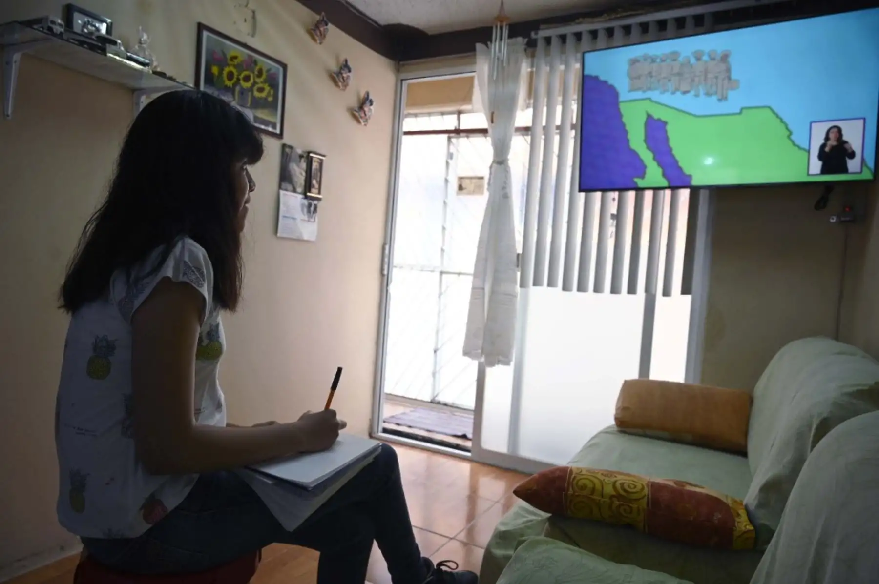La estudiante de secundaria Vanessa Villegas, toma clase frente a su televisor en su casa, en la Ciudad de México. Unos 30 millones de estudiantes mexicanos iniciaron este lunes un nuevo año escolar con clases transmitidas por televisión debido al nuevo coronavirus. Foto: AFP