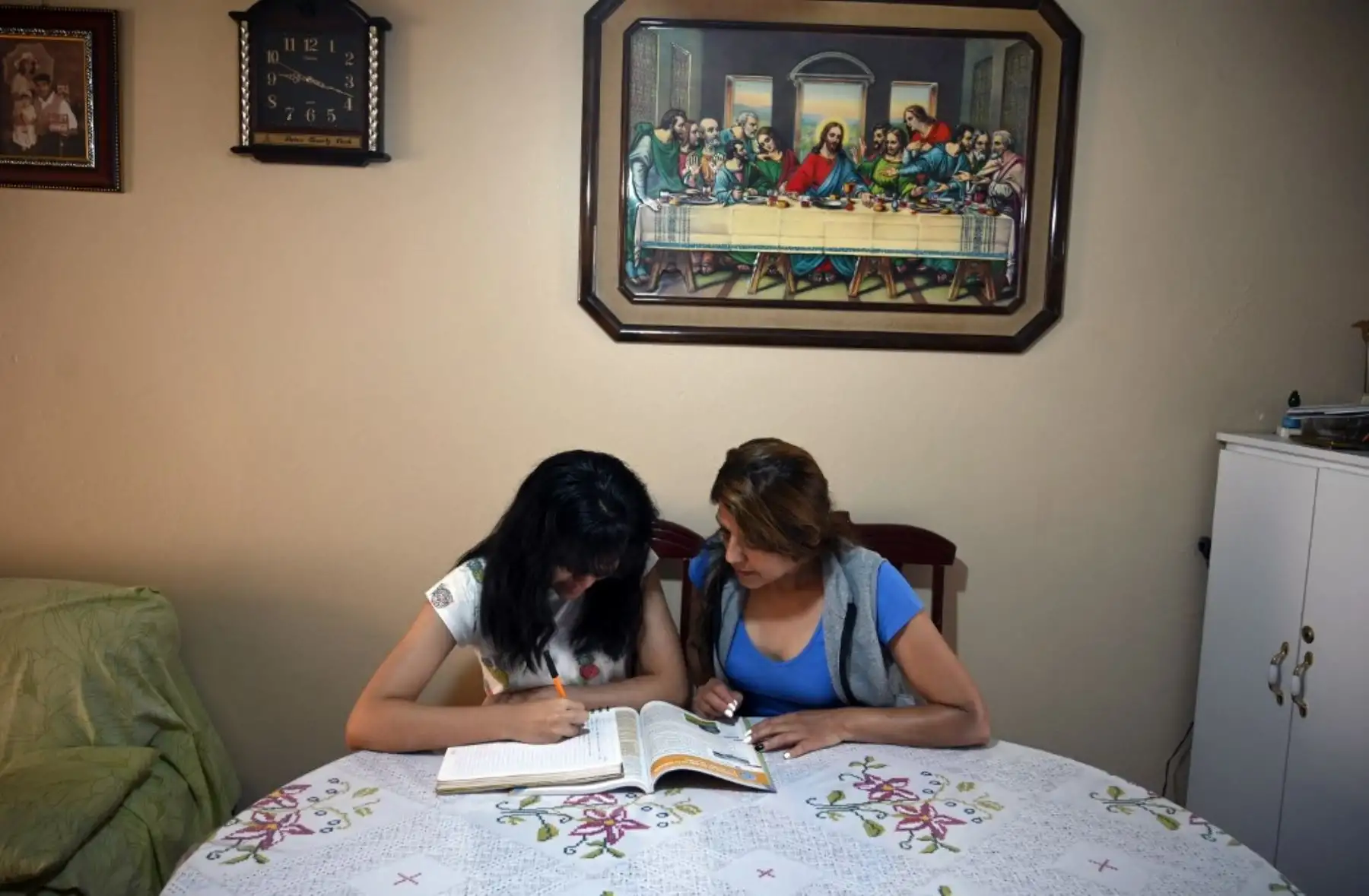 La estudiante de secundaria Vanessa Villegas es ayudada por su madre Norma Portales mientras toma una clase frente a su televisor en su casa, en la Ciudad de México. Unos 30 millones de estudiantes mexicanos comenzaron un nuevo año escolar el Lunes con clases retransmitidas por televisión por la nueva pandemia de coronavirus. Foto: AFP