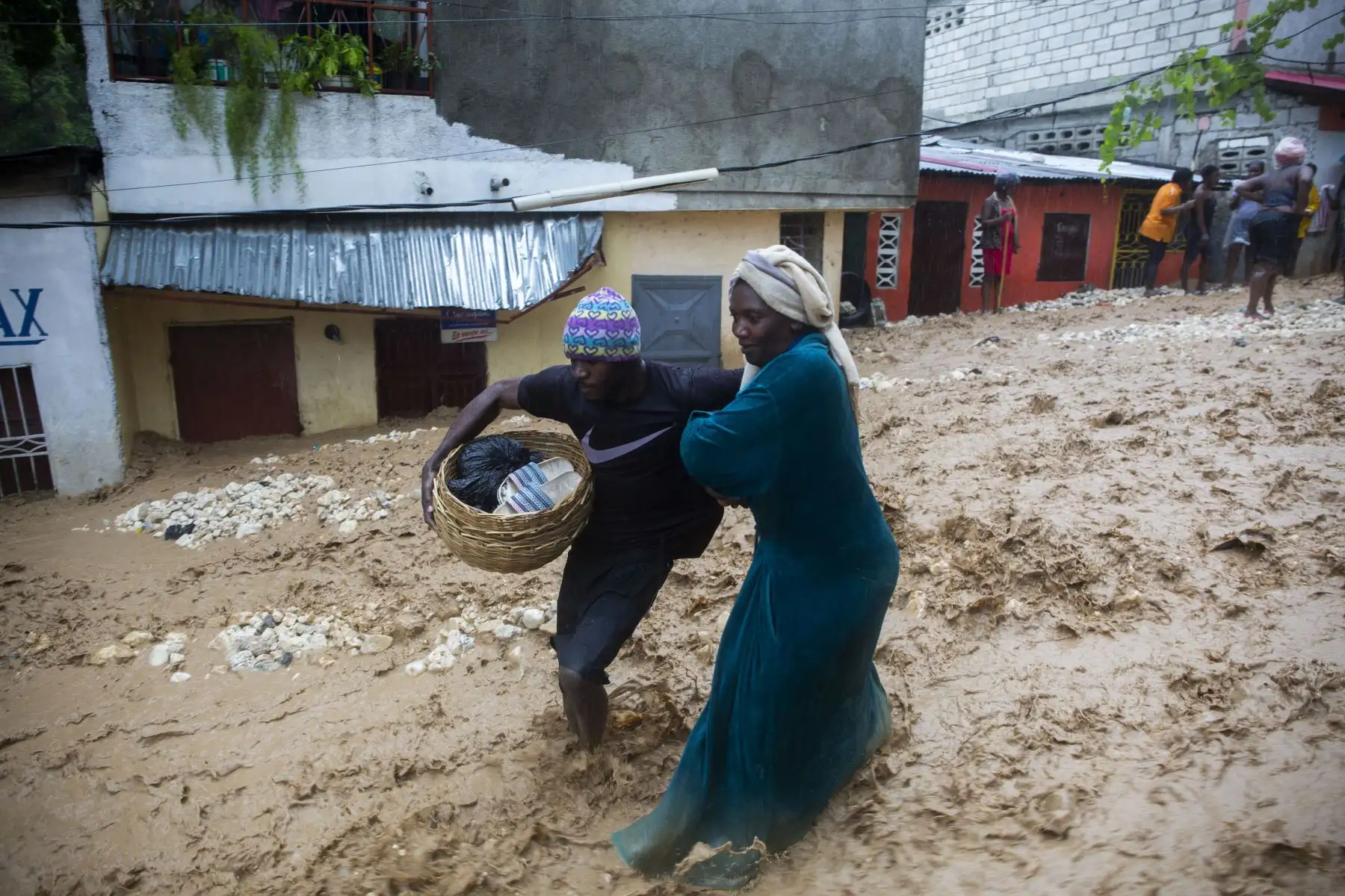 Personas vendiendo en el mercado caminan por la calle inundada en el barrio de Pétion ville, Haití, durante el paso de la tormenta tropical Laura. Foto: AFP