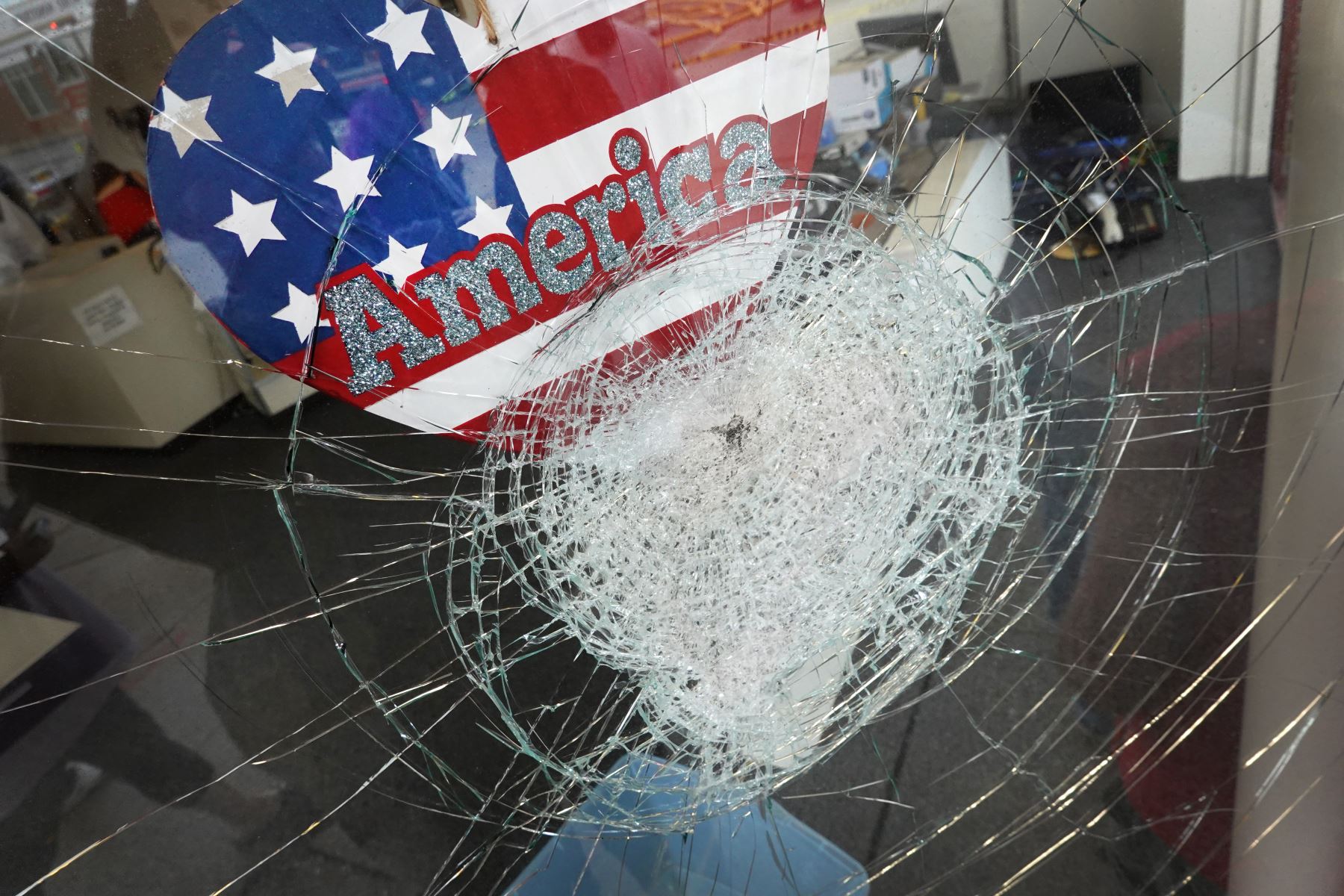 Una pegatina de la bandera estadounidense se observa en la ventana quebrada de una tienda, tras otra noche de disturbios después de que un oficial de policía le disparara a Jacob Blake, un afroestadounidense desarmado, siete veces en la espalda frente a sus tres menores hijos. Foto: AFP.