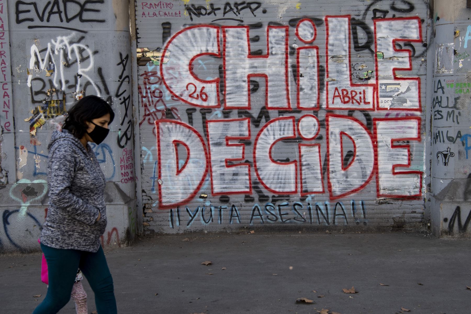 Una mujer pasa junto a un grafiti que dice "Chile decide", en referencia al referéndum del 25 de octubre para cambiar la Constitución de la era de la dictadura militar de Chile, en Santiago. Foto: AFP.