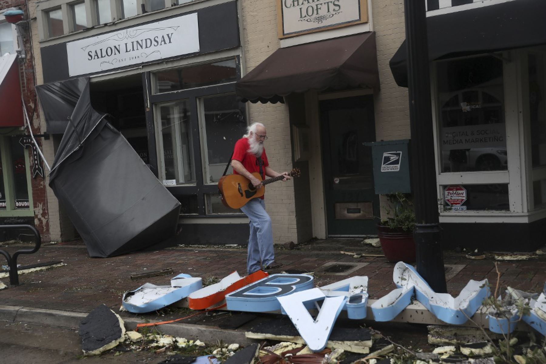 Un hombre toca su guitarra mientras camina por el centro de la ciudad, después del paso del huracán Laura en Lake Charles, Louisiana. Foto:AFP
