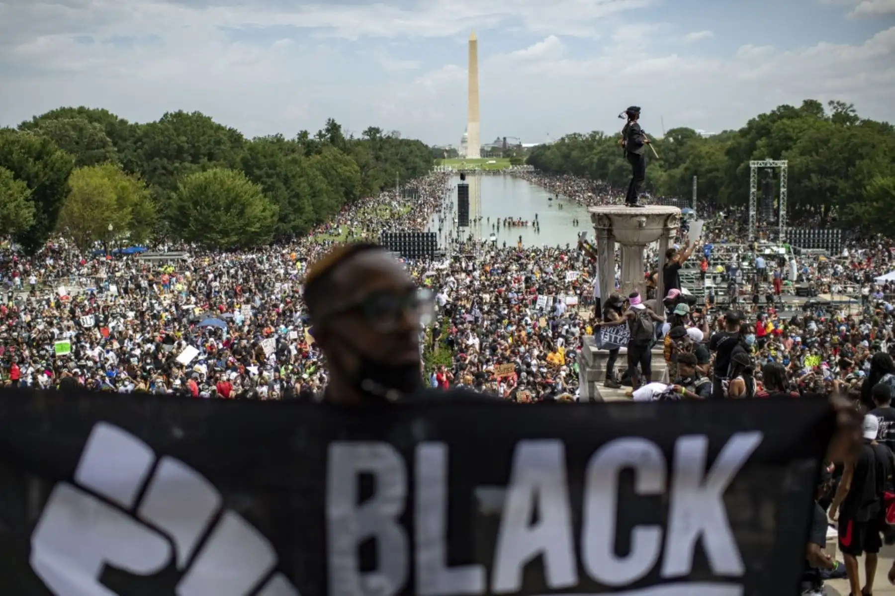 Un hombre muestra una pancarta mientras la gente asiste a la protesta "Marcha por el compromiso: quítese la rodilla del cuello" contra el racismo y la brutalidad policial, en el Lincoln Memorial en Washington, DC. Foto:AFP