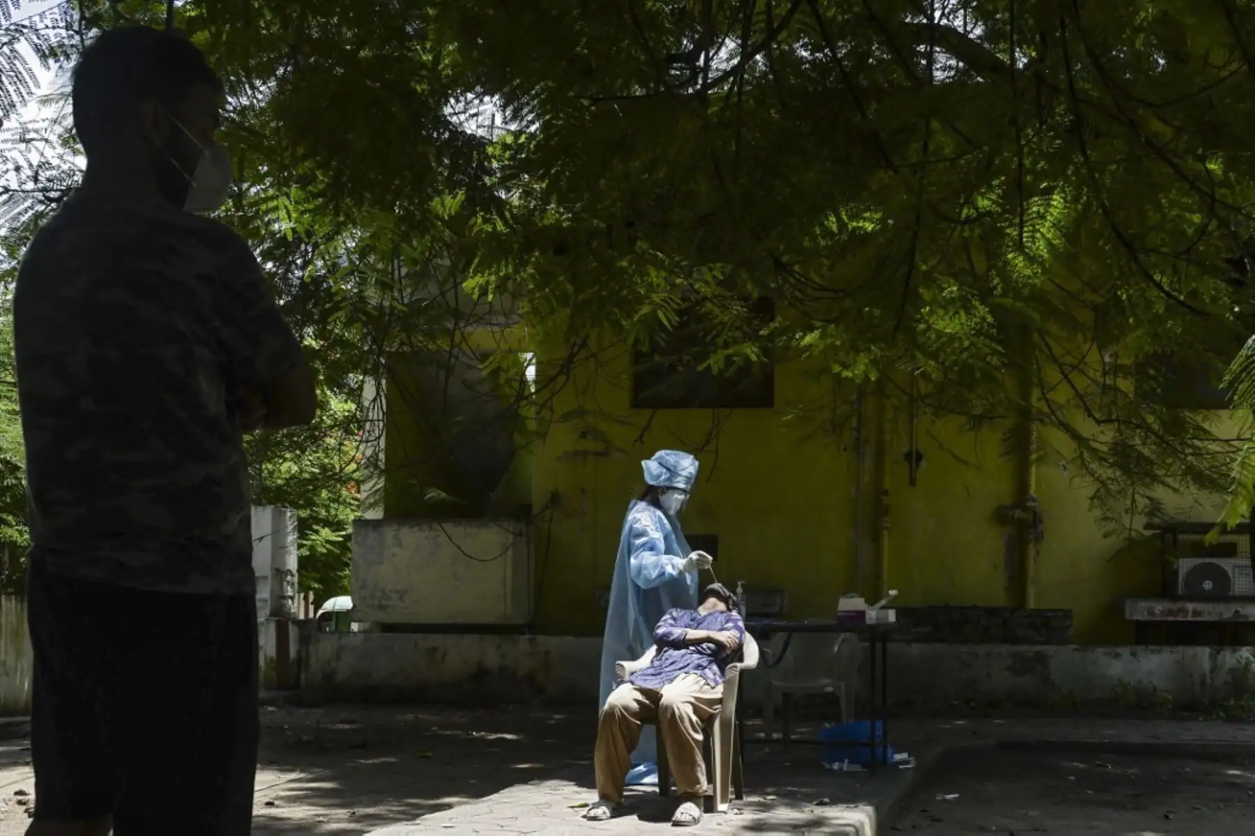 Un trabajador de la salud que usa equipo de protección personal (EPP) recolecta una muestra de hisopo de una mujer para una prueba gratuita de coronavirus Covid-19 en un parque de la Corporación Municipal en Hyderabad, India. Foto: AFP