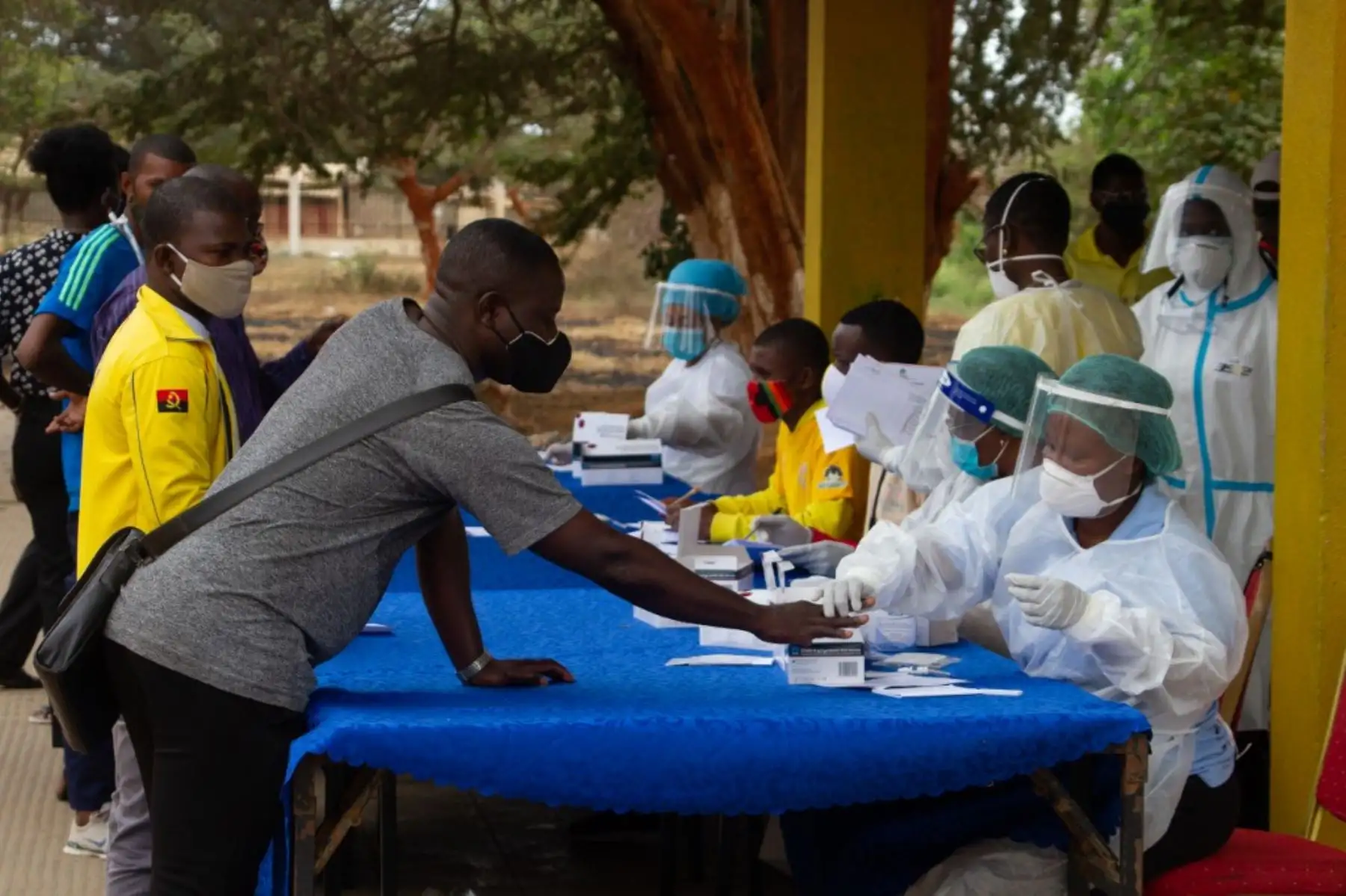 Un trabajador de la salud con equipo de protección personal (EPP) pincha la mano de un hombre durante un ejercicio de prueba masiva del coronavirus covid-19 para taxistas en el Marco Histórico do Cazenga en Luanda. Foto: AFP